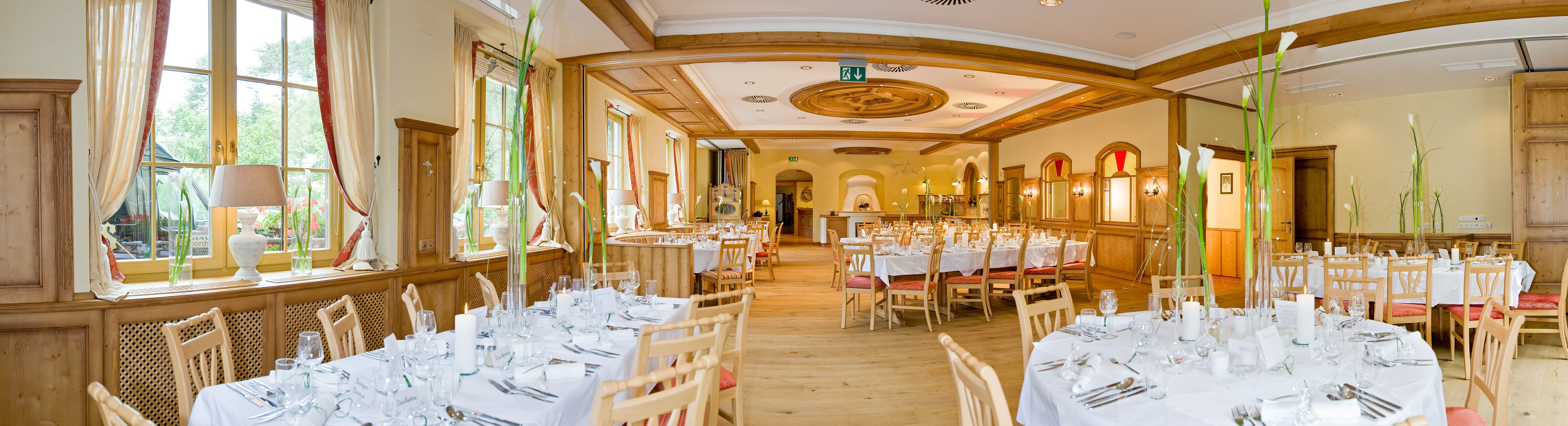Elegant dining room with laid tables and wood paneling.