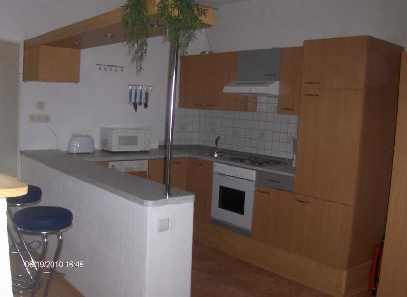 Modern kitchen with wooden cupboards, bar stools and appliances such as microwave and stove.