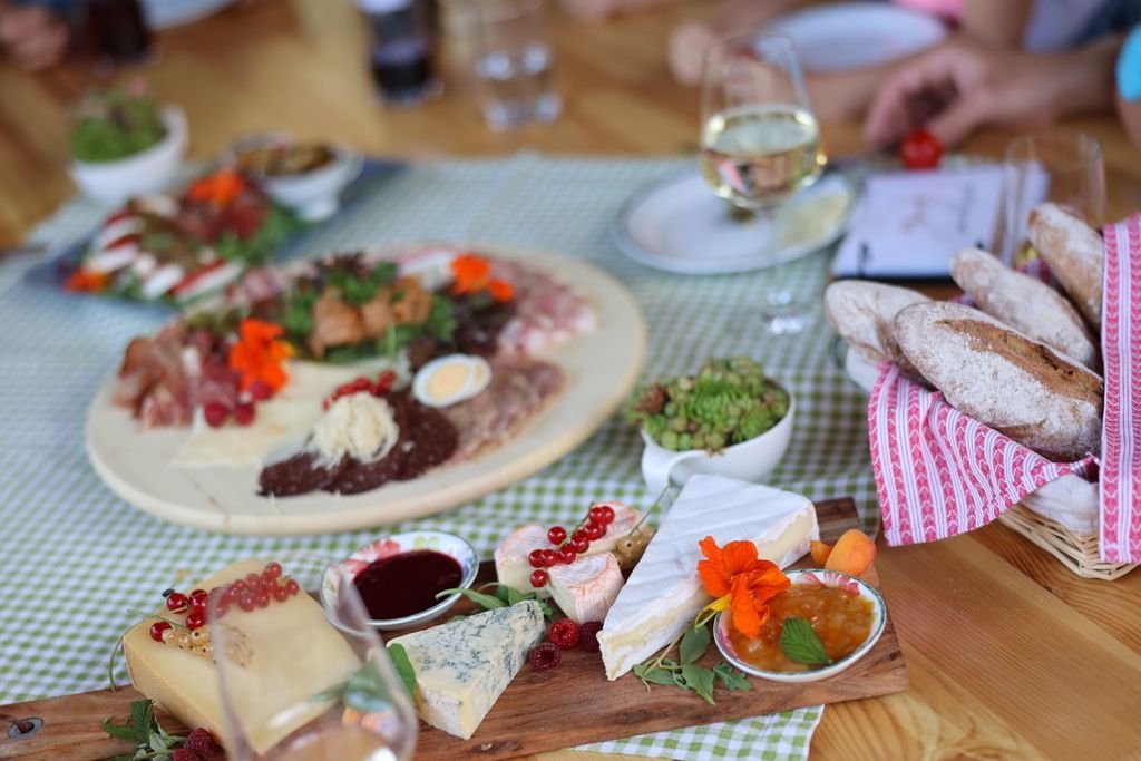 A laid table with cheese platter, bread, cold cuts and wine.
