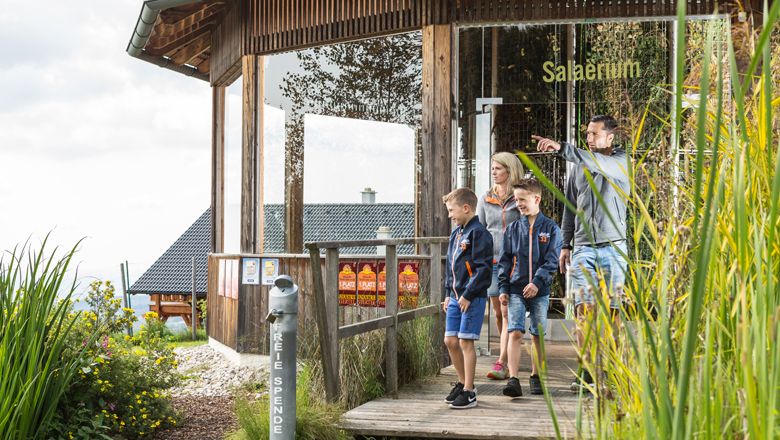 Family on a wooden path in front of a building with the inscription 'Salaerium'.