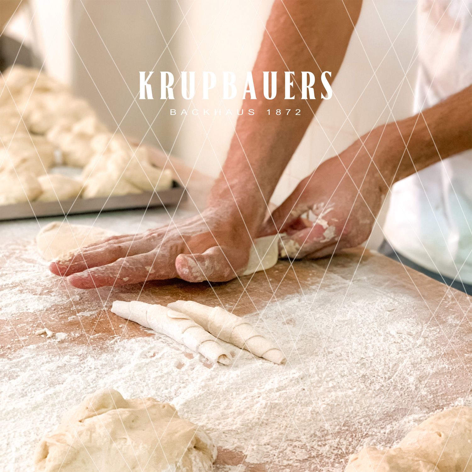 Person shaping dough on a floured table in a bakery.