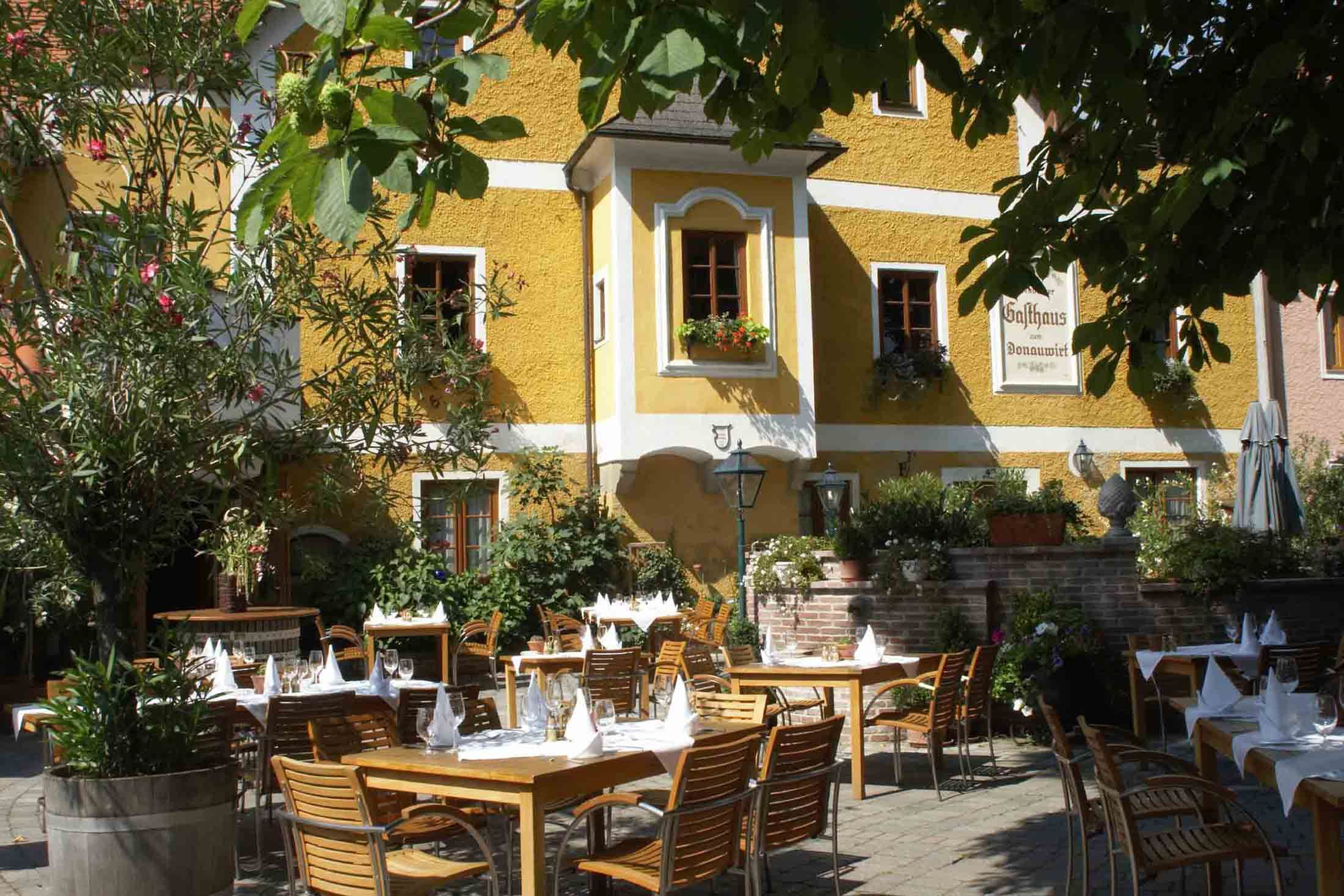 Terrace of an inn with laid tables and plants.