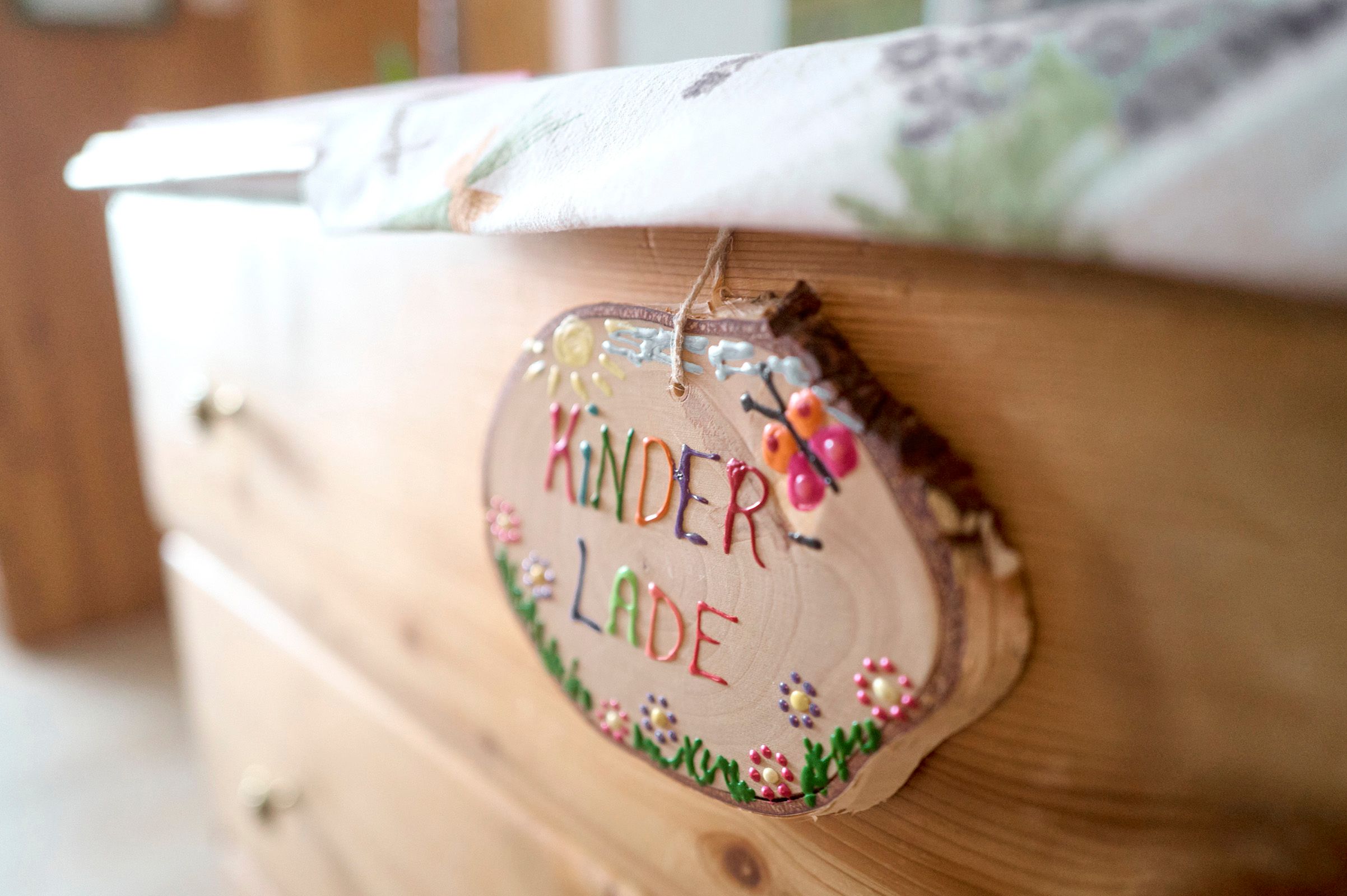 Close-up of a wooden sign with the inscription 'Kinderlade' on a chest of drawers.