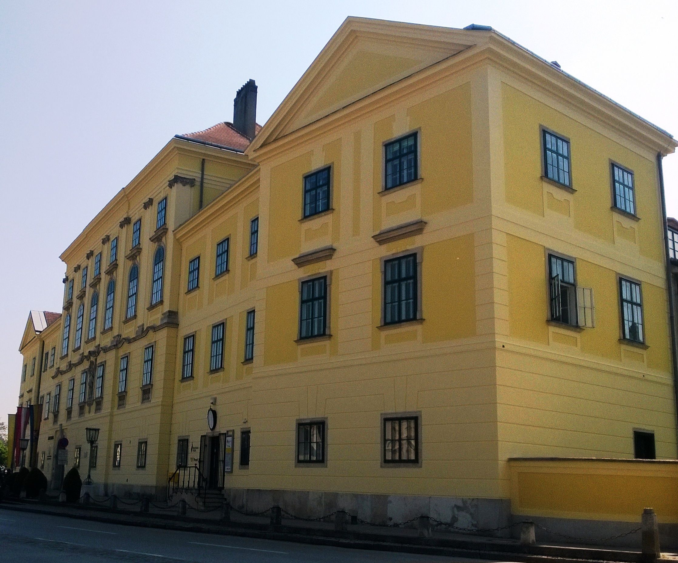 Yellow historic building with many windows and a gabled roof.
