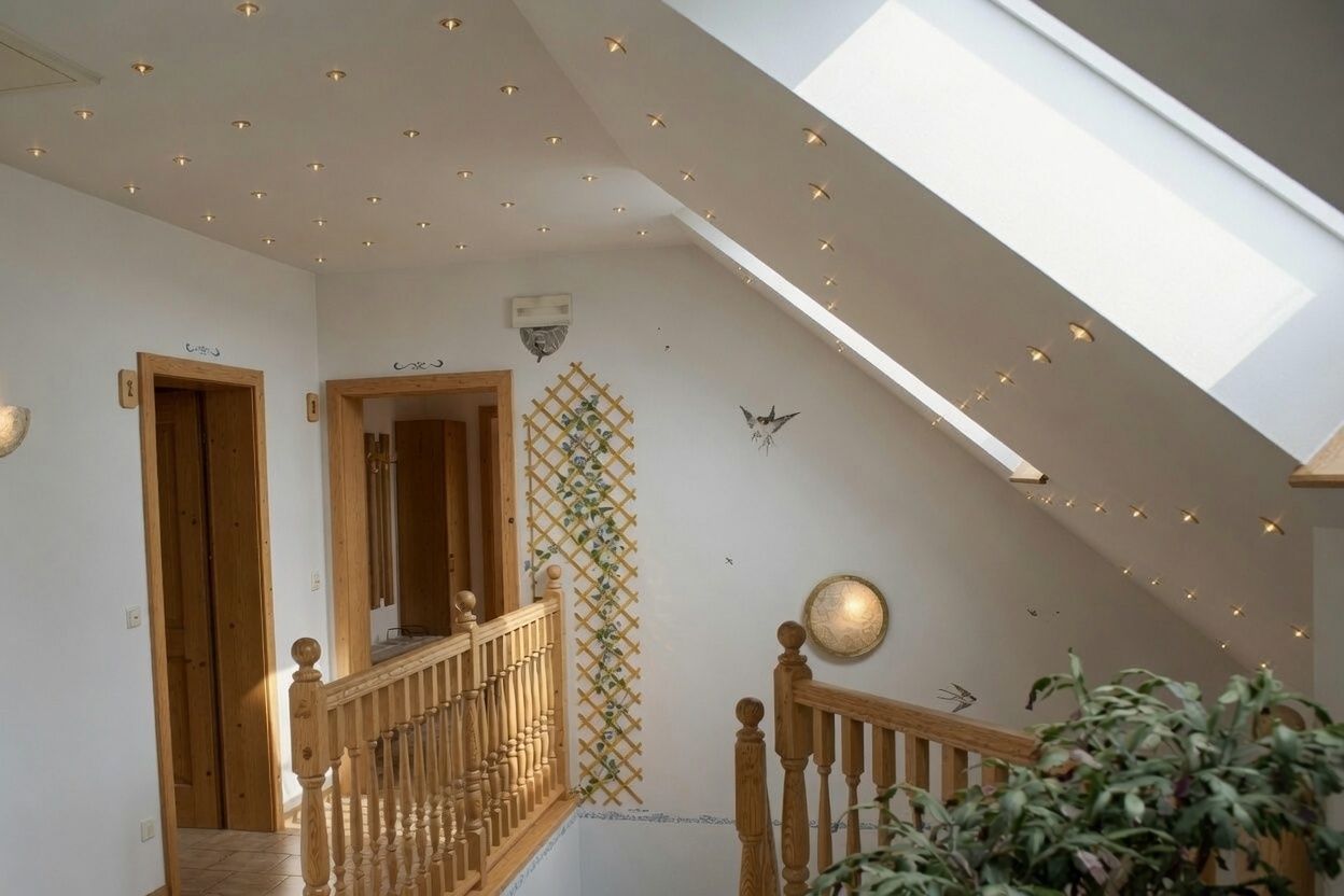 A bright hallway with wooden railings and skylight, decorated with murals of birds and plants.