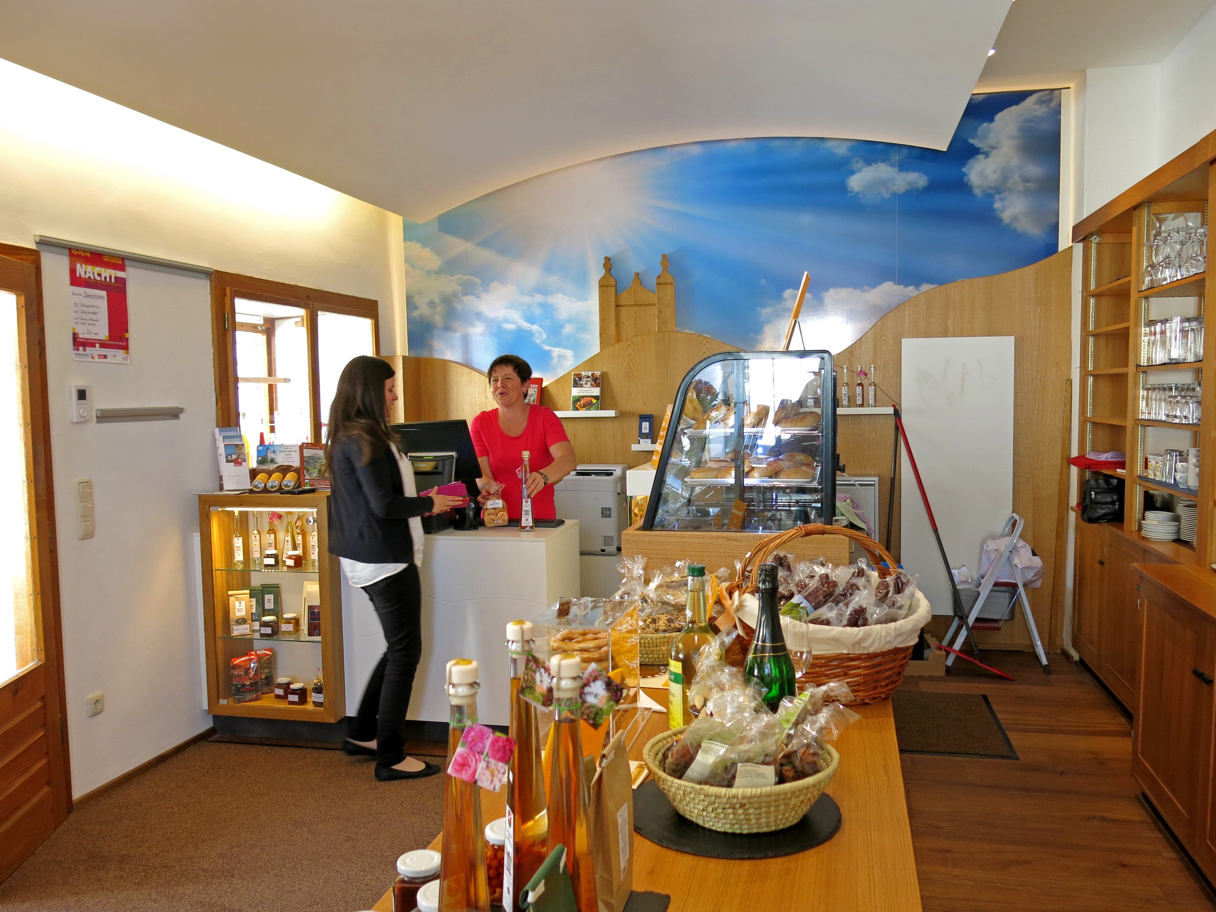 Interior view of a visitor center with two women at the counter and various products on a table.
