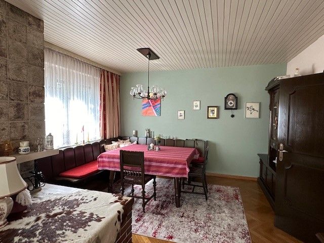 Cozy living room with dining table, corner bench, carpet and wall clock.