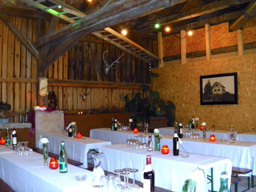 Rustic function room with wooden walls, laid tables and decorations.