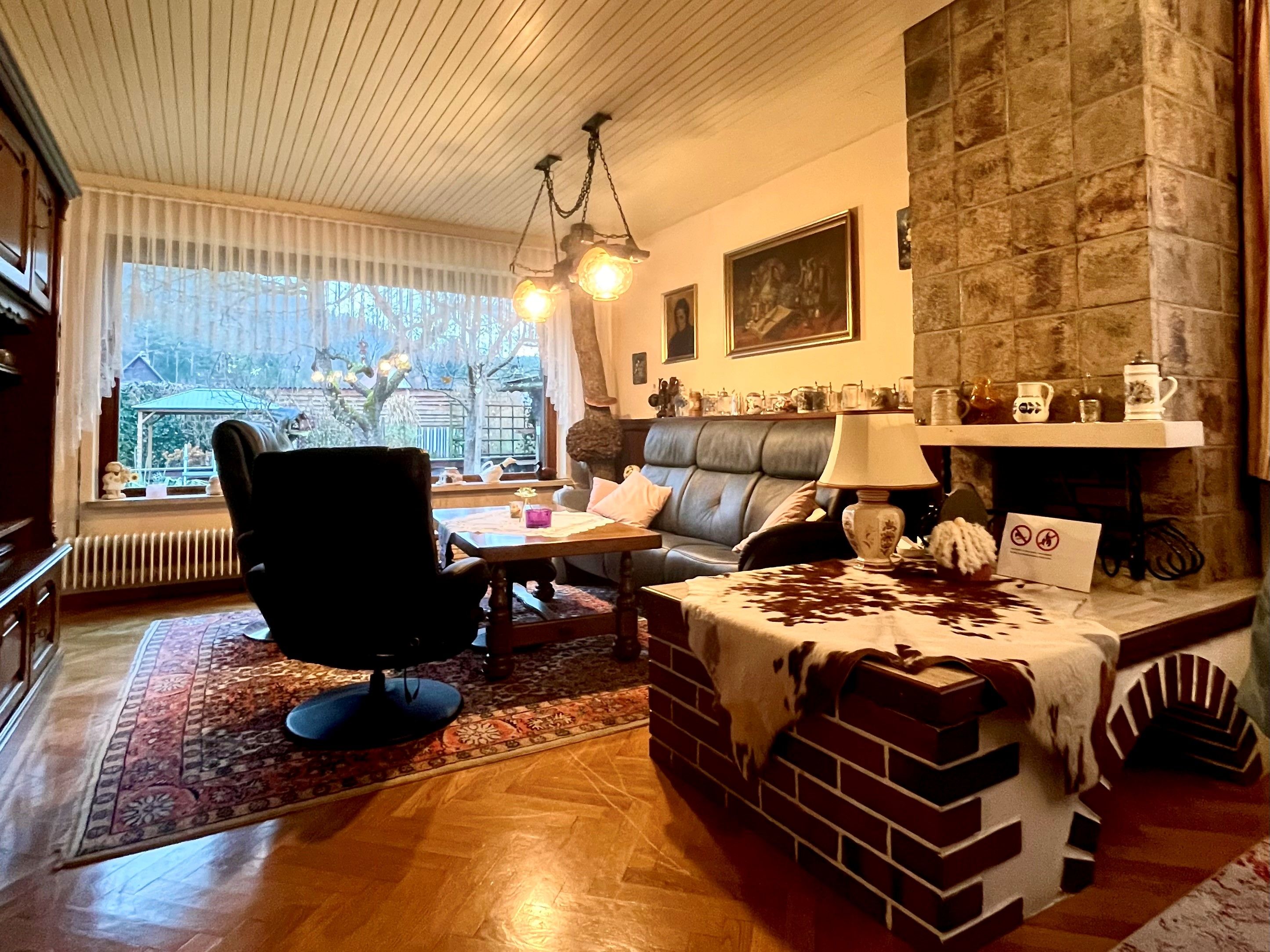 Cozy living room with leather sofa, fireplace, carpet and large windows overlooking the garden.