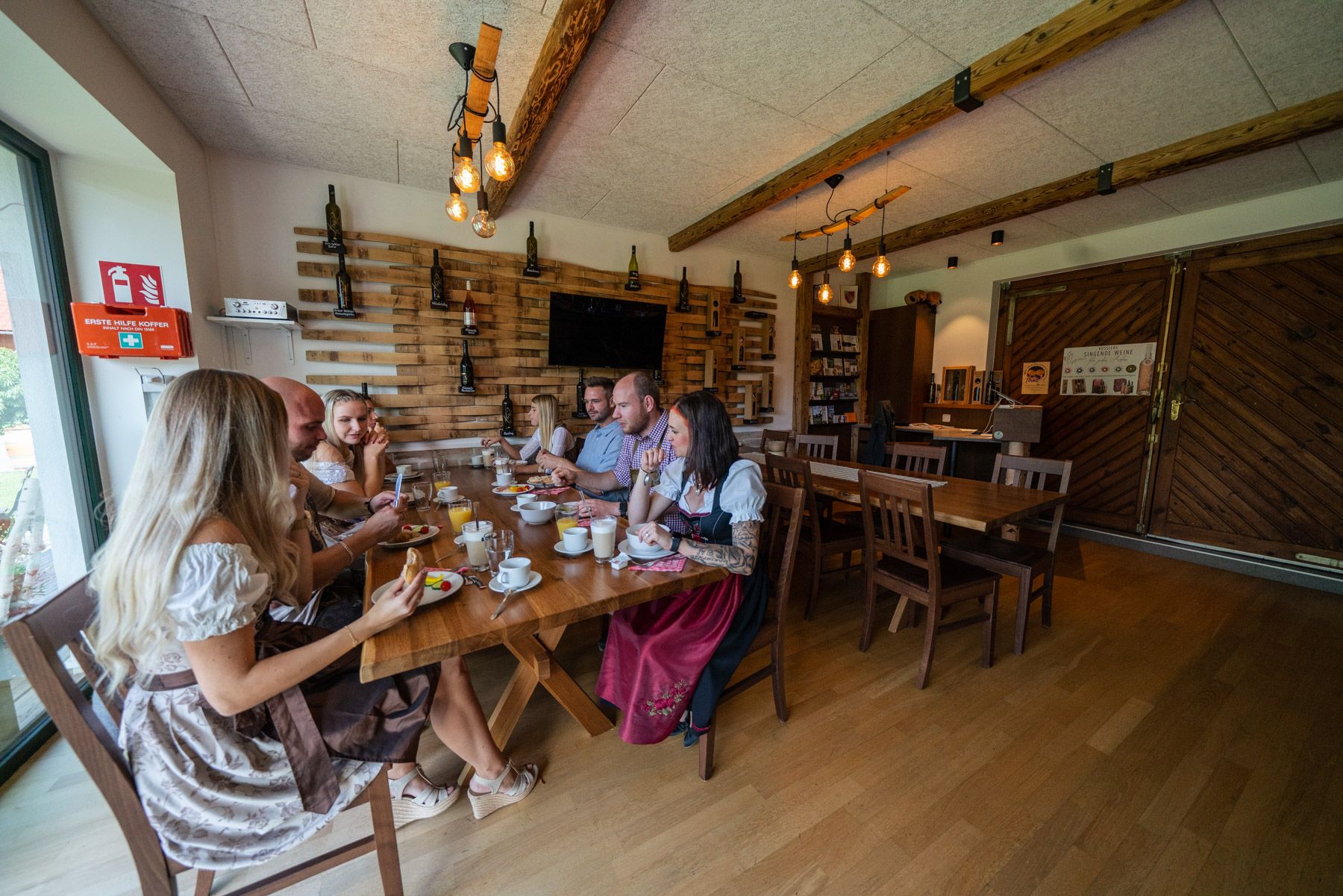 Group of people in traditional dress sitting at a table in a rustic room.