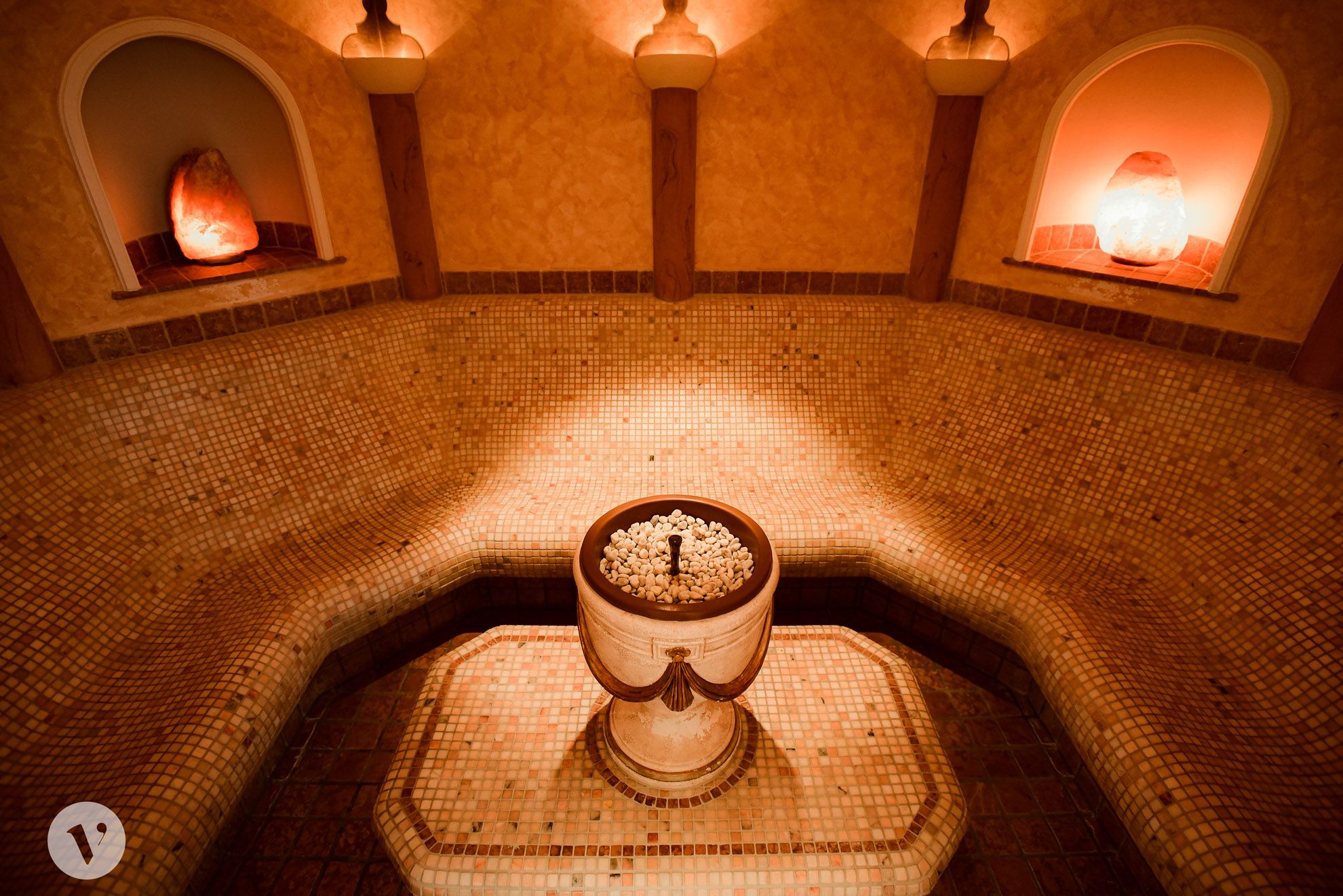 A laconium with mosaic tiles, a central fountain and warm light.