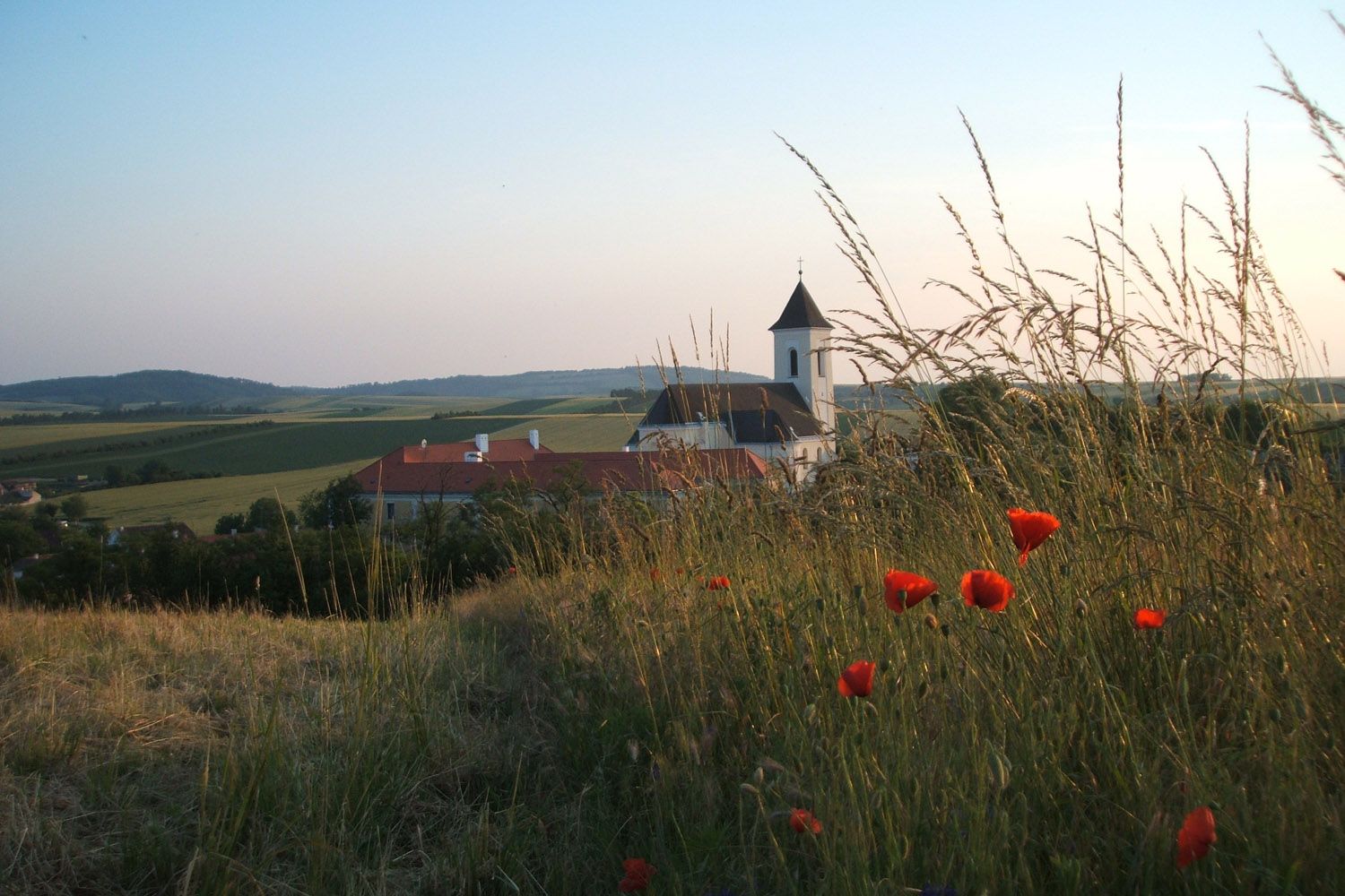 Landscape with church and poppies in the foreground.