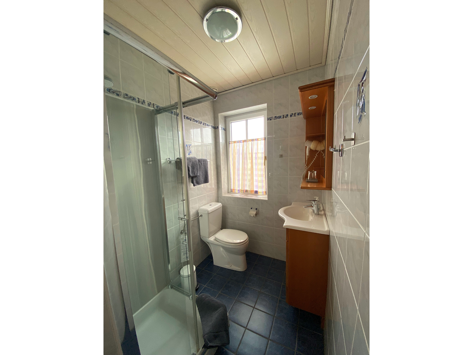 Small bathroom with shower, toilet and washbasin.