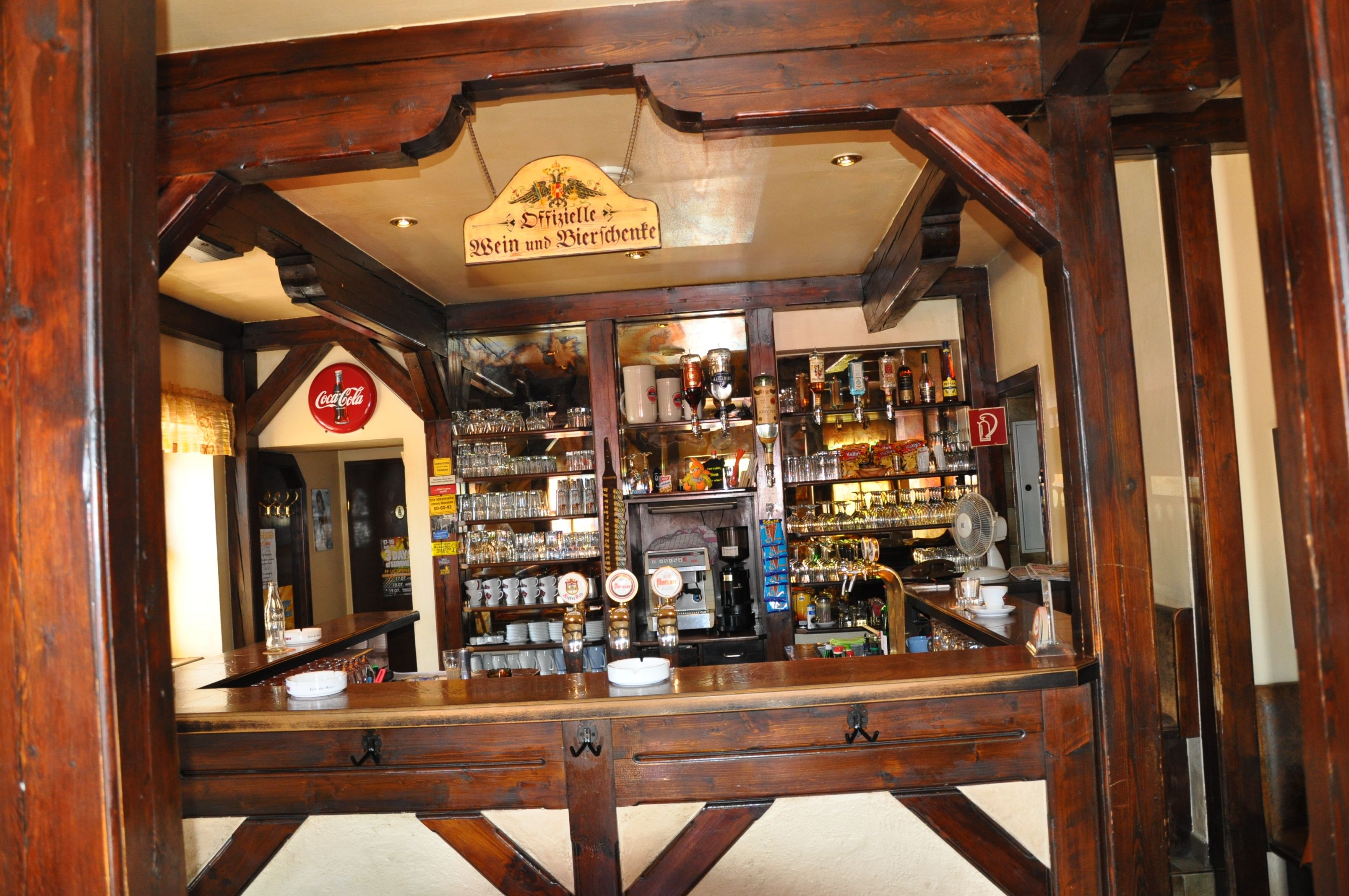 Interior view of a rustic bar with wooden beams and a well-stocked counter.