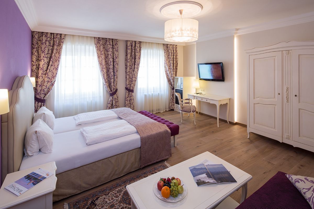 Elegant hotel room with double bed, desk, TV and fruit plate.