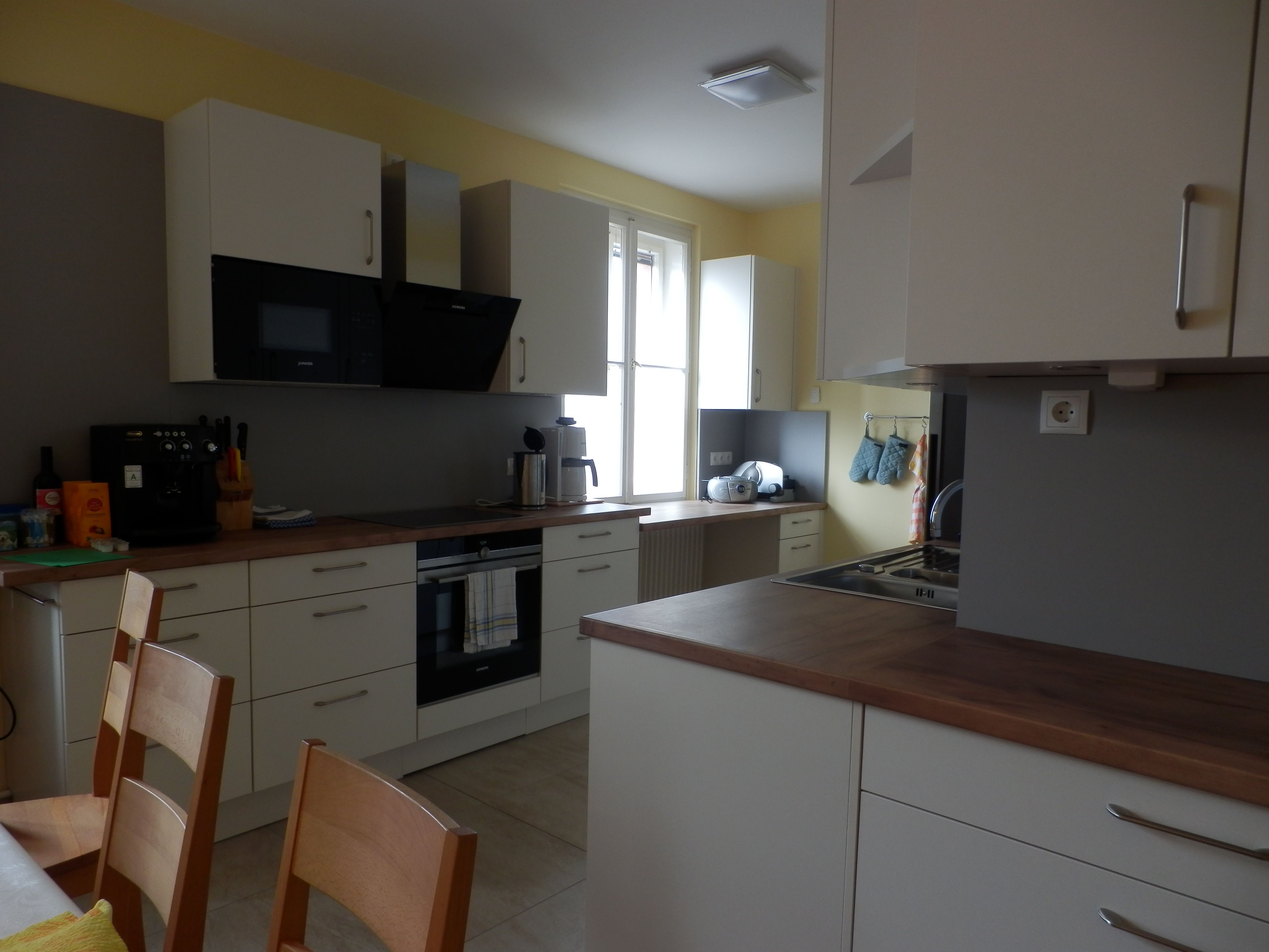 Modern kitchen with white cupboards, wooden worktops and appliances such as coffee machine and oven.