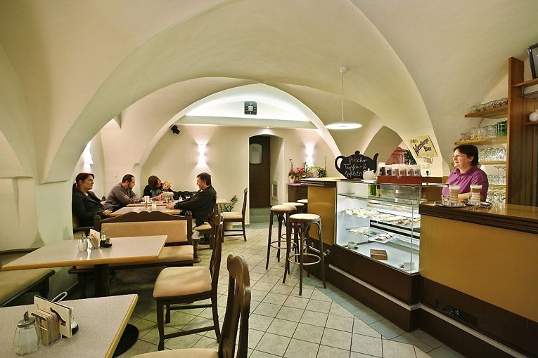 Interior view of a cozy café with a vaulted ceiling, tables and a bar.