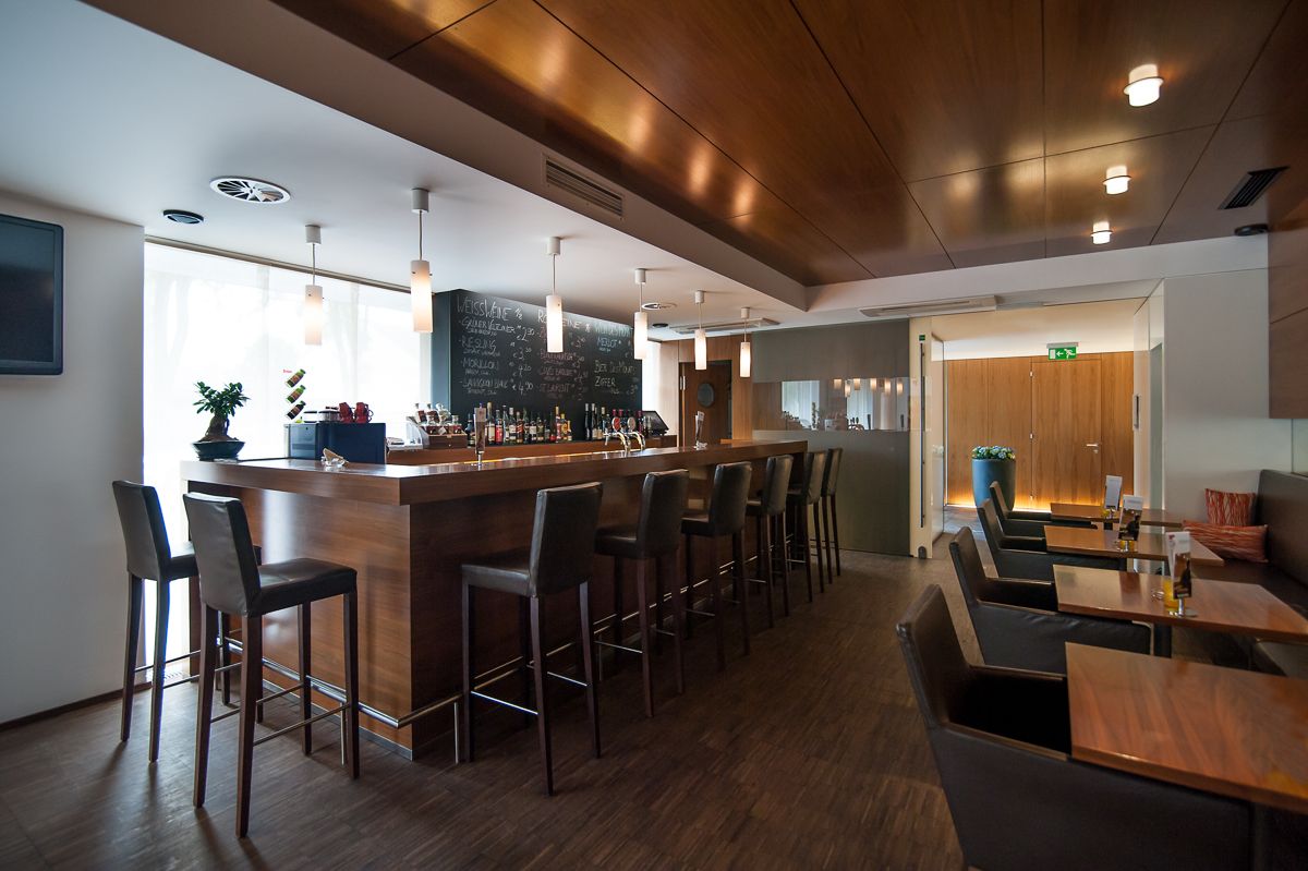 Modern bar with wooden counter and high stools.