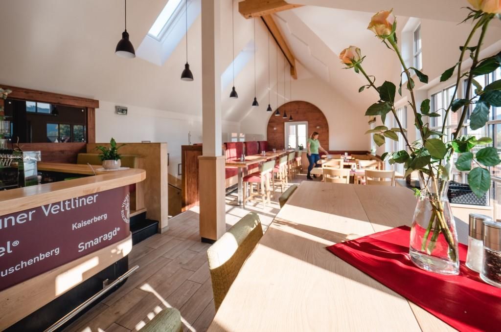 Interior view of a modern wine tavern with wooden furniture and large windows.