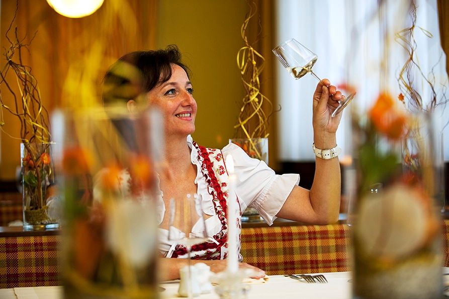 Woman in traditional dress holding a wine glass in a restaurant.