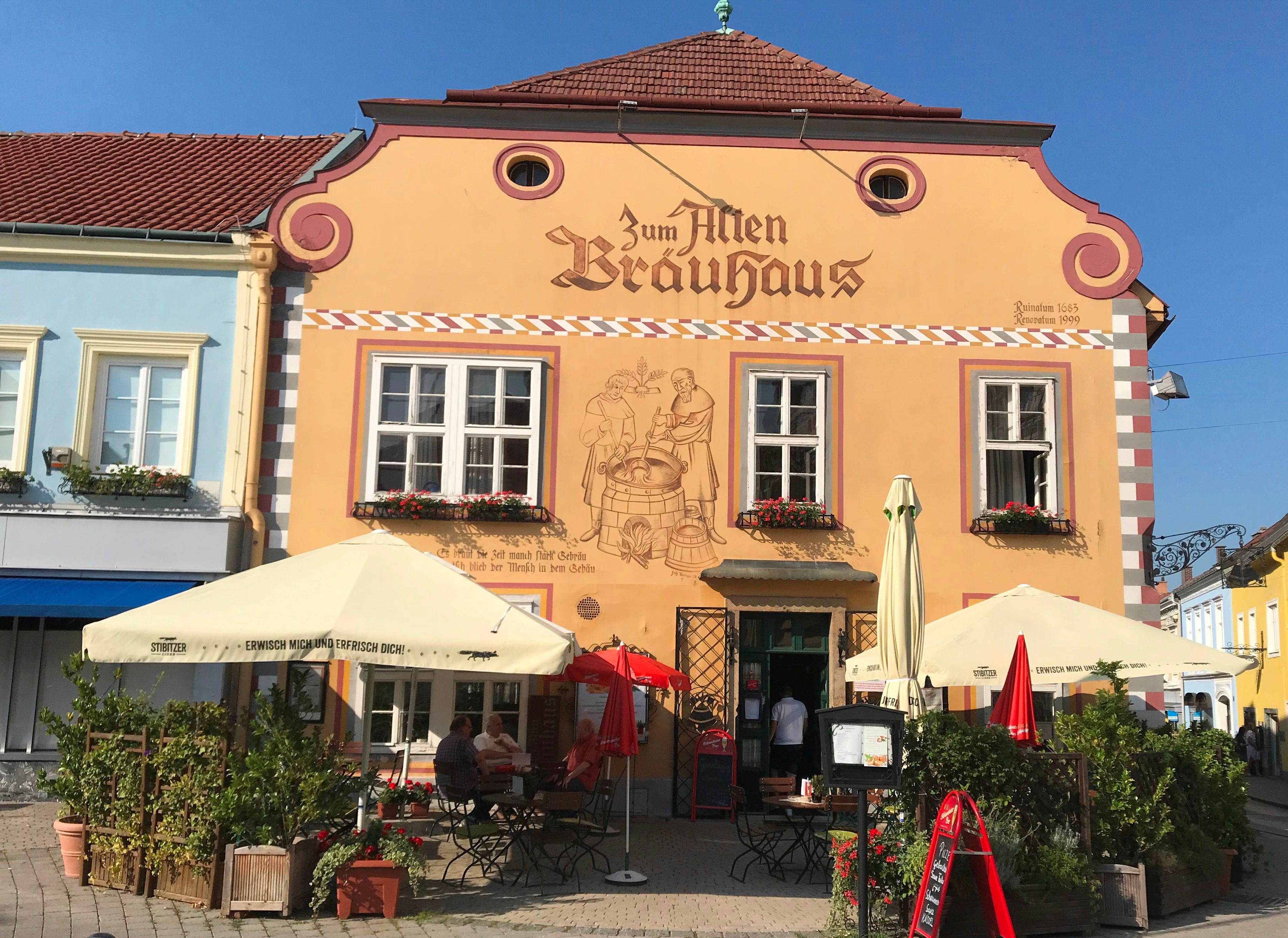 Façade of a traditional brewery with parasols and outdoor seating area.