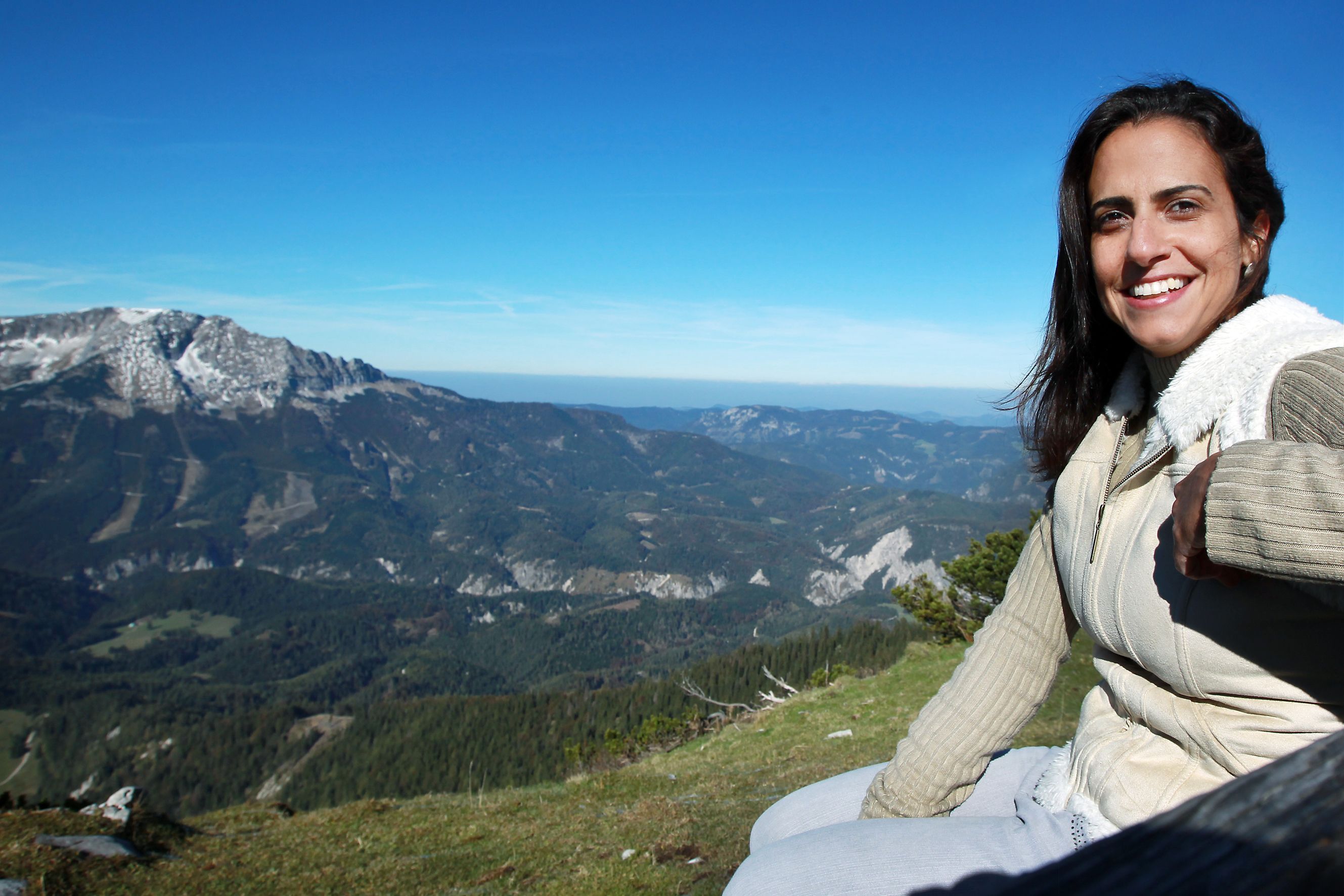 Woman sitting on a mountain with a view of a mountain landscape.