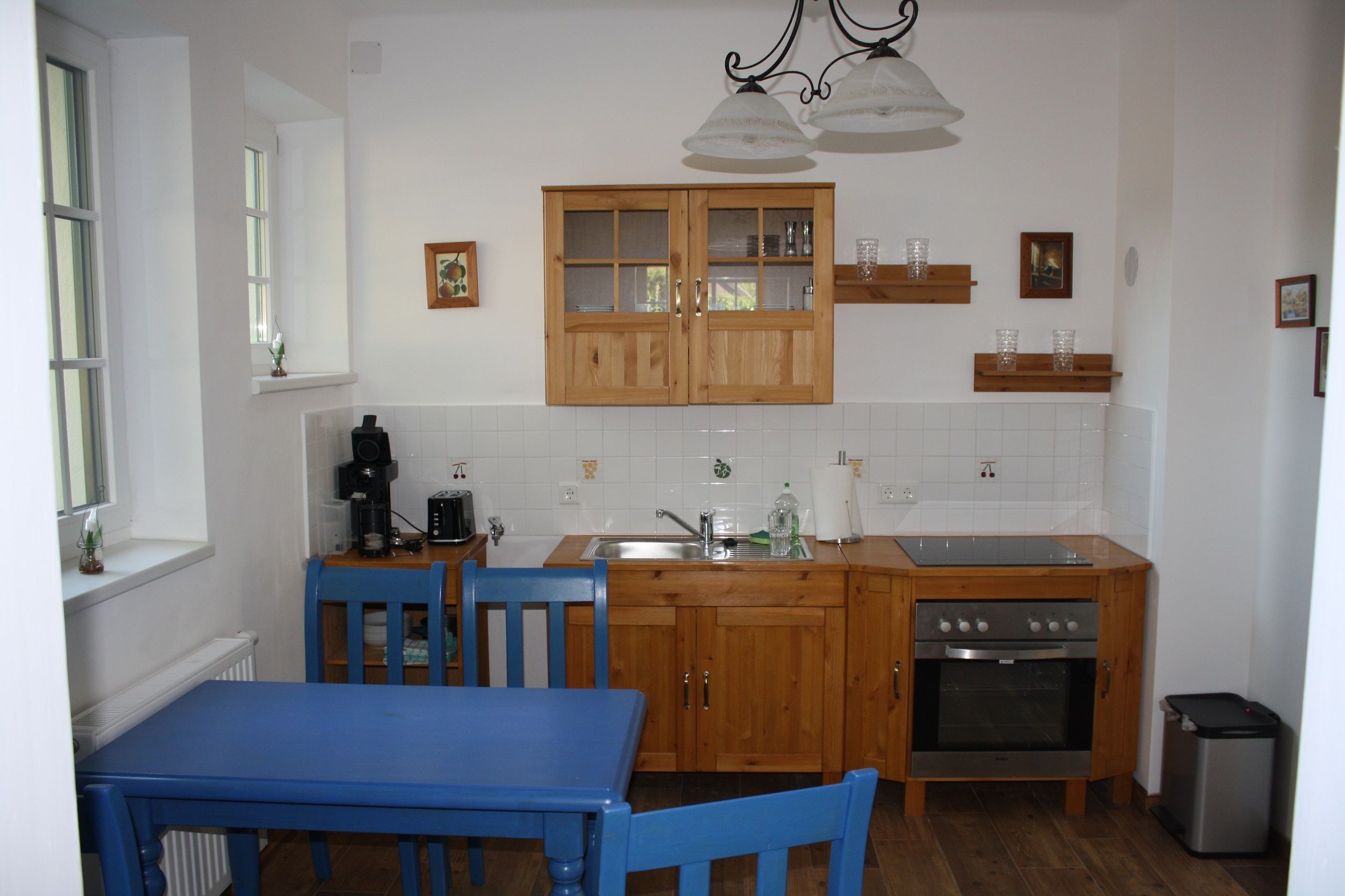 Kitchen in a vacation apartment with wooden furniture, blue chairs and modern equipment.