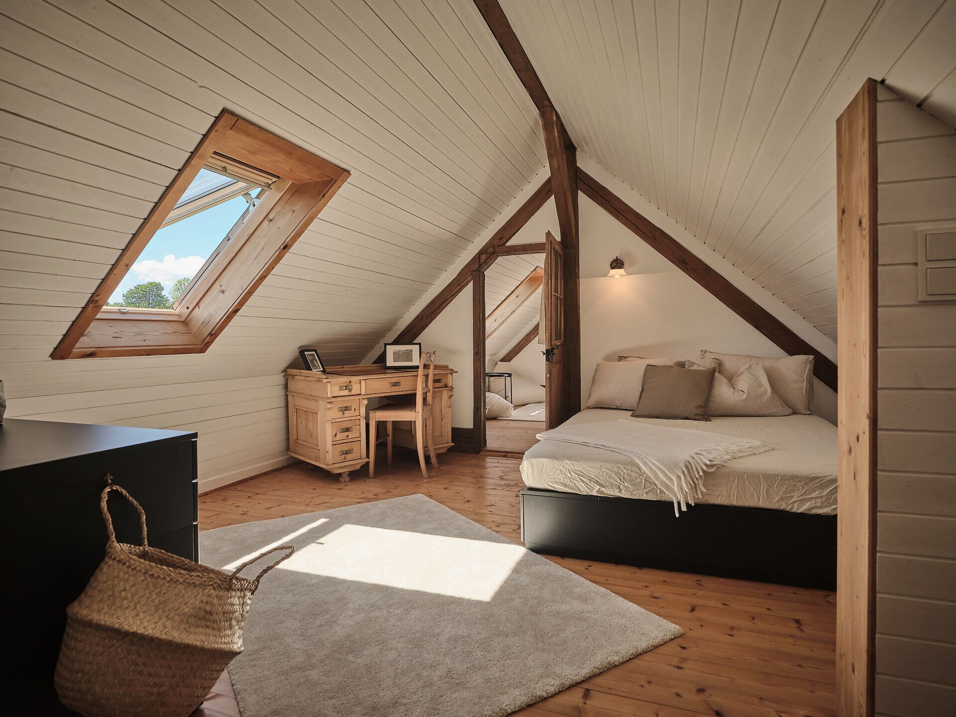 Rustic stone house with wooden door, bench and flowers in the foreground.