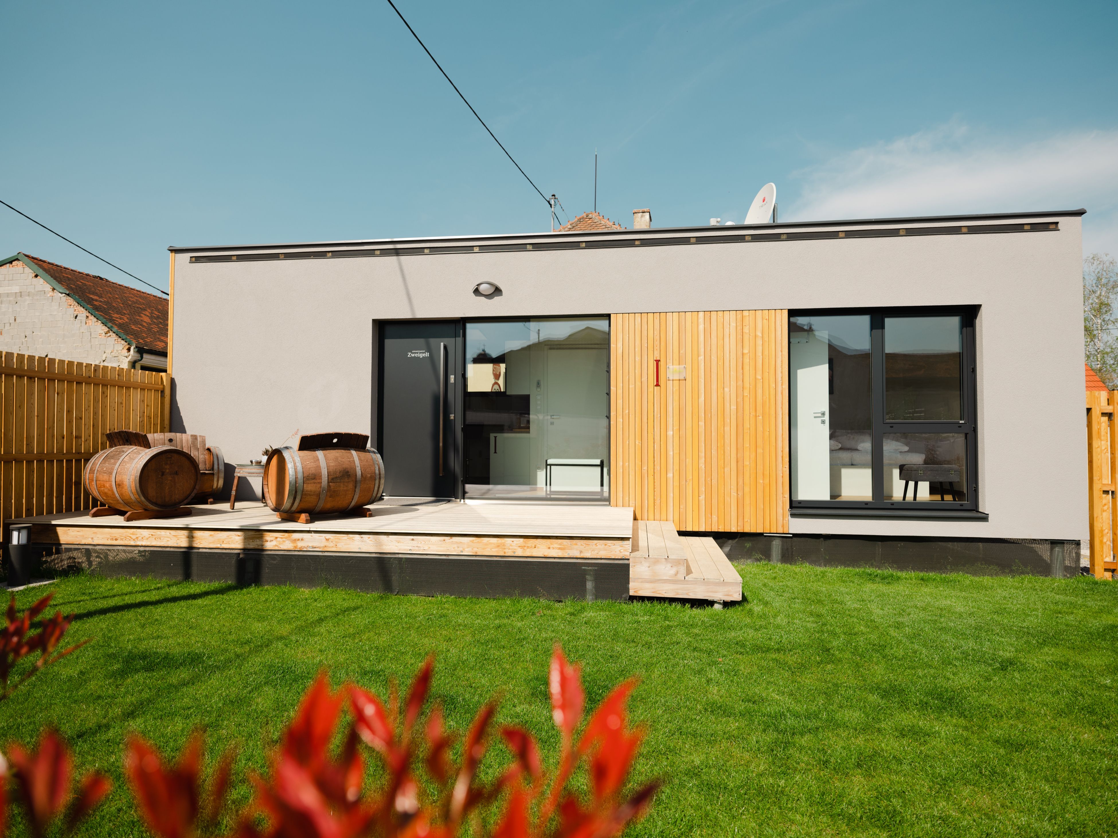 Modern building with terrace and wine barrels in the garden.