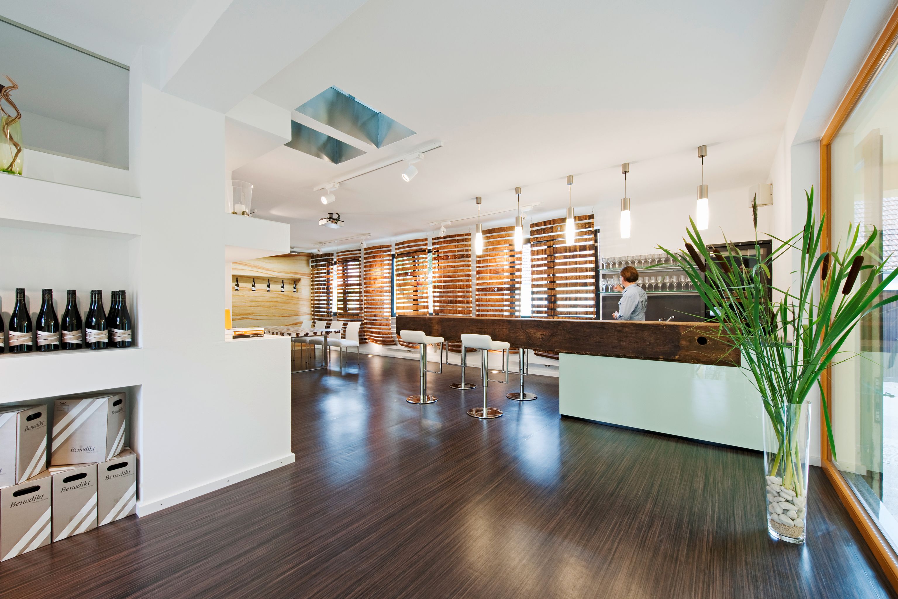 Modern tasting room with bar, chairs and wine bottles.