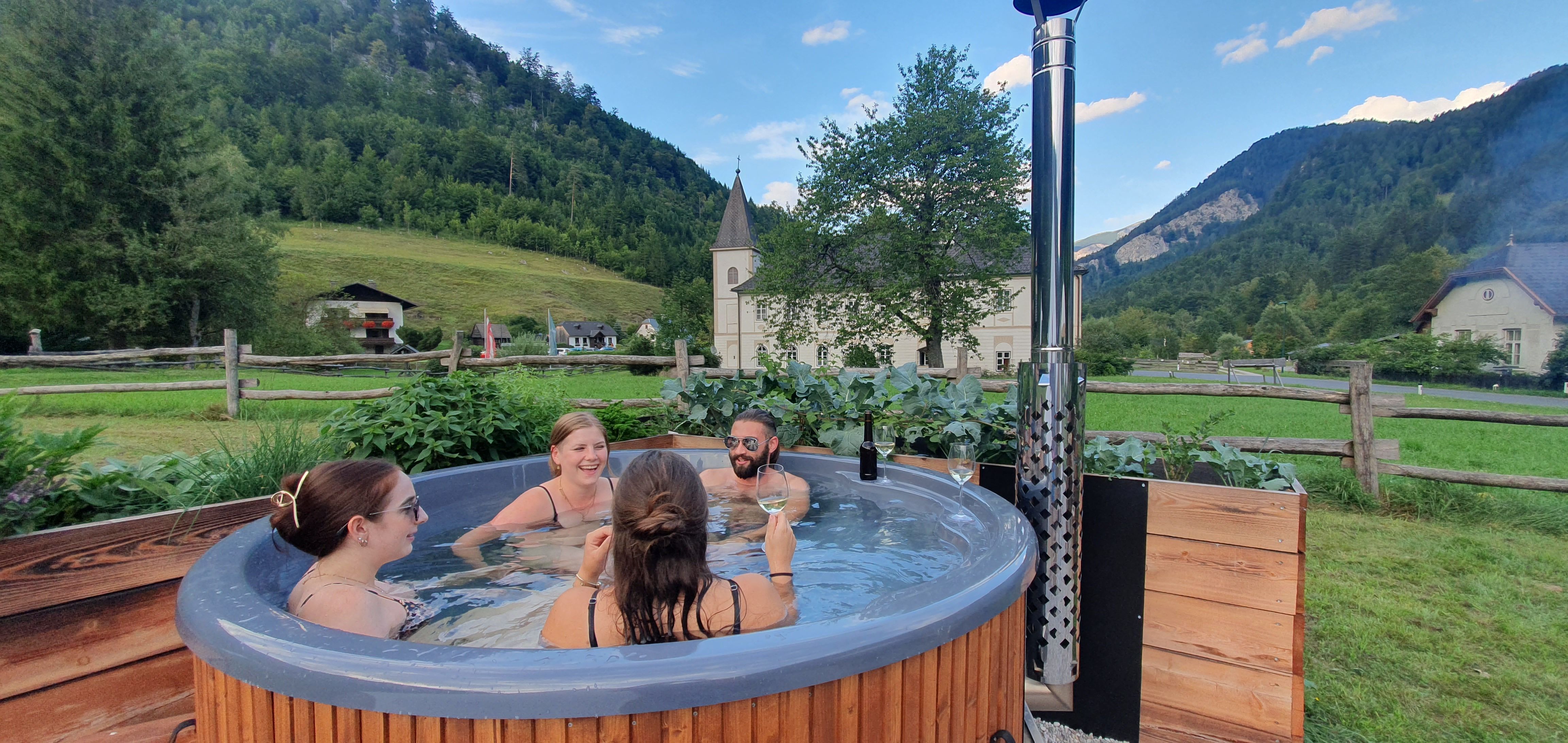 Group of people in a hot tub in a rural setting.