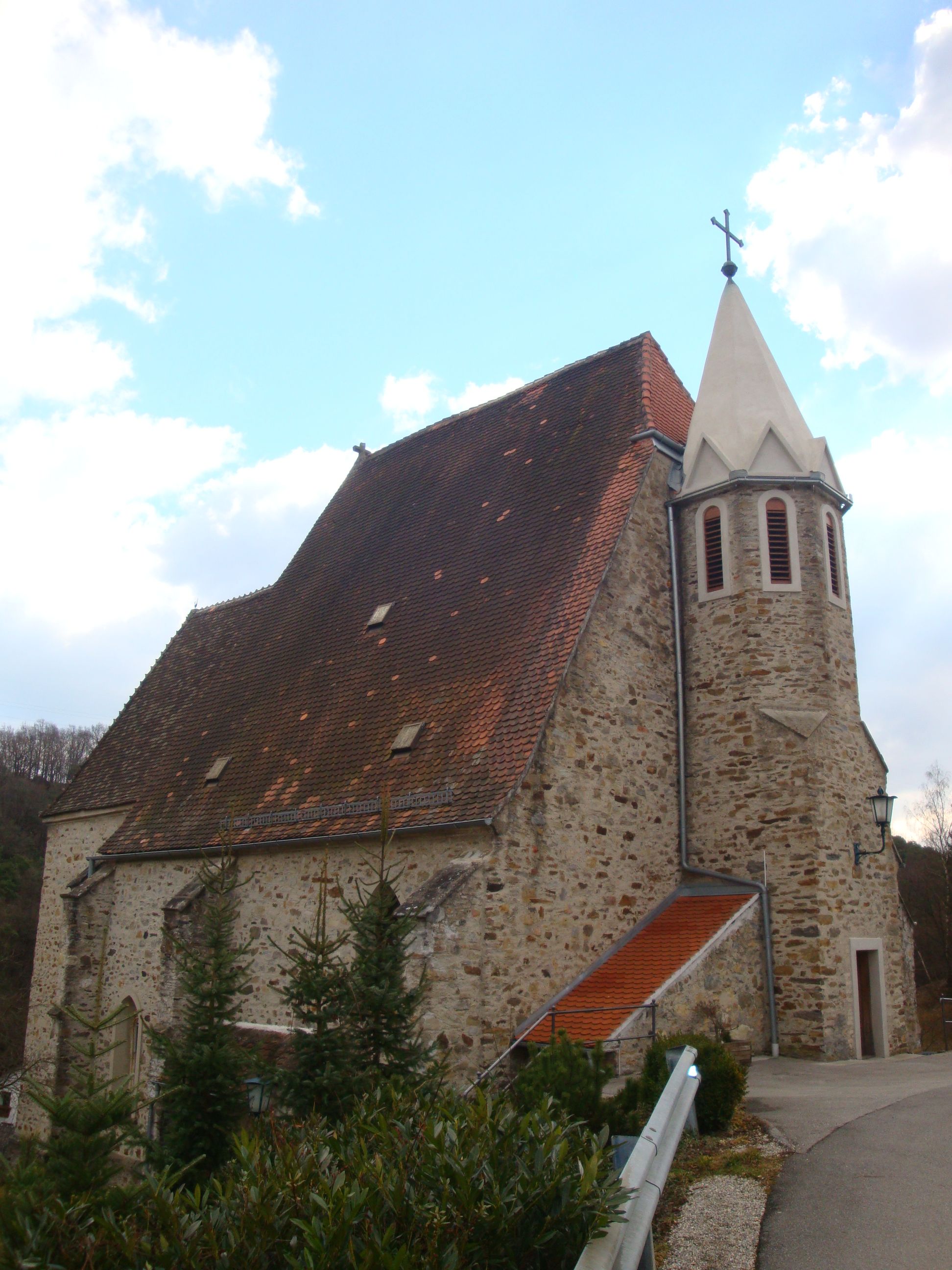 Pöbring parish church with steep roof and tower against a blue sky.