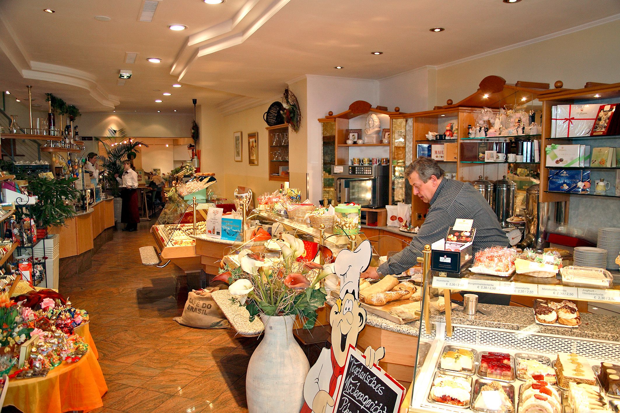 Interior view of a cozy café with a counter full of cakes and pastries.