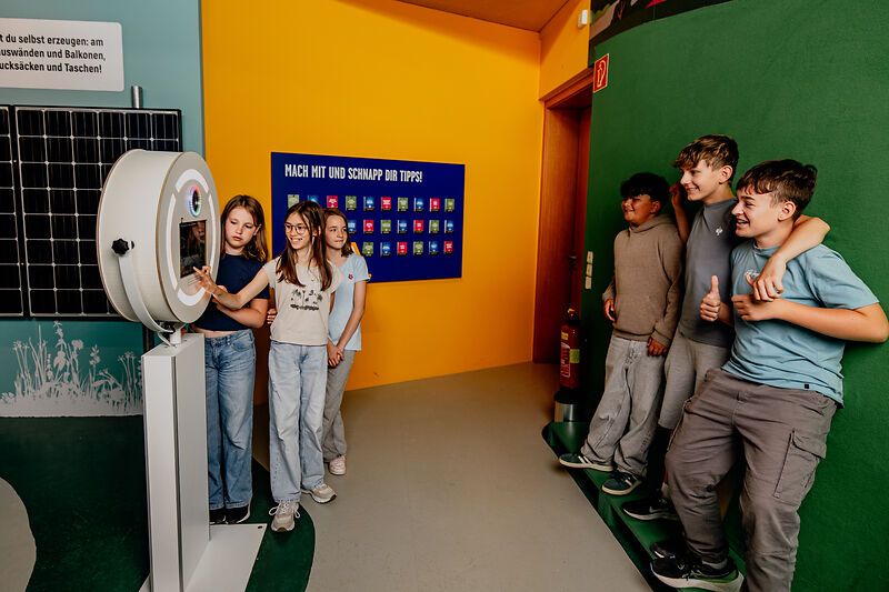 Group of young people interacting with the photo box in front of a green screen