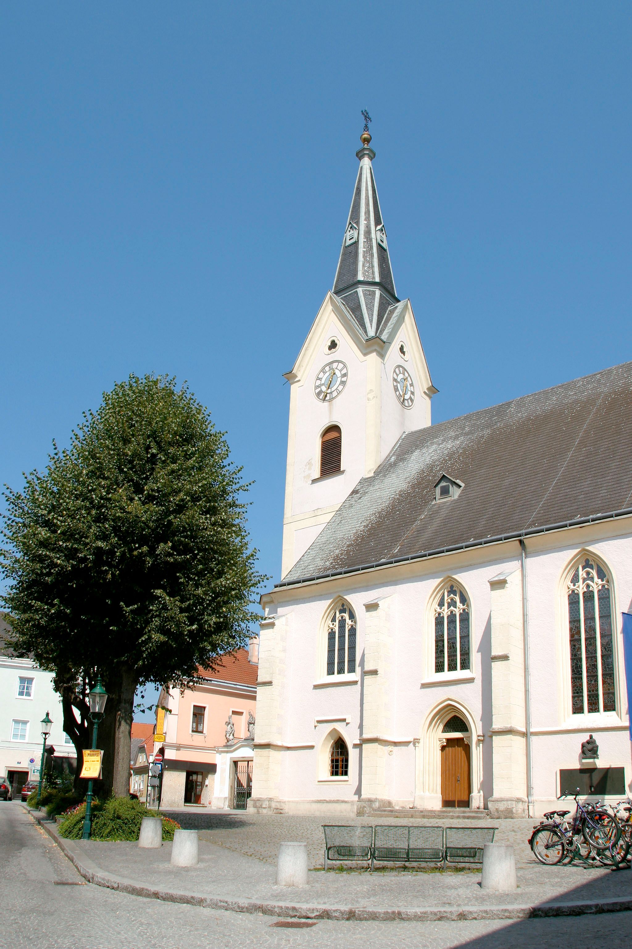 St. Laurenz parish church with tower and clock against a blue sky.