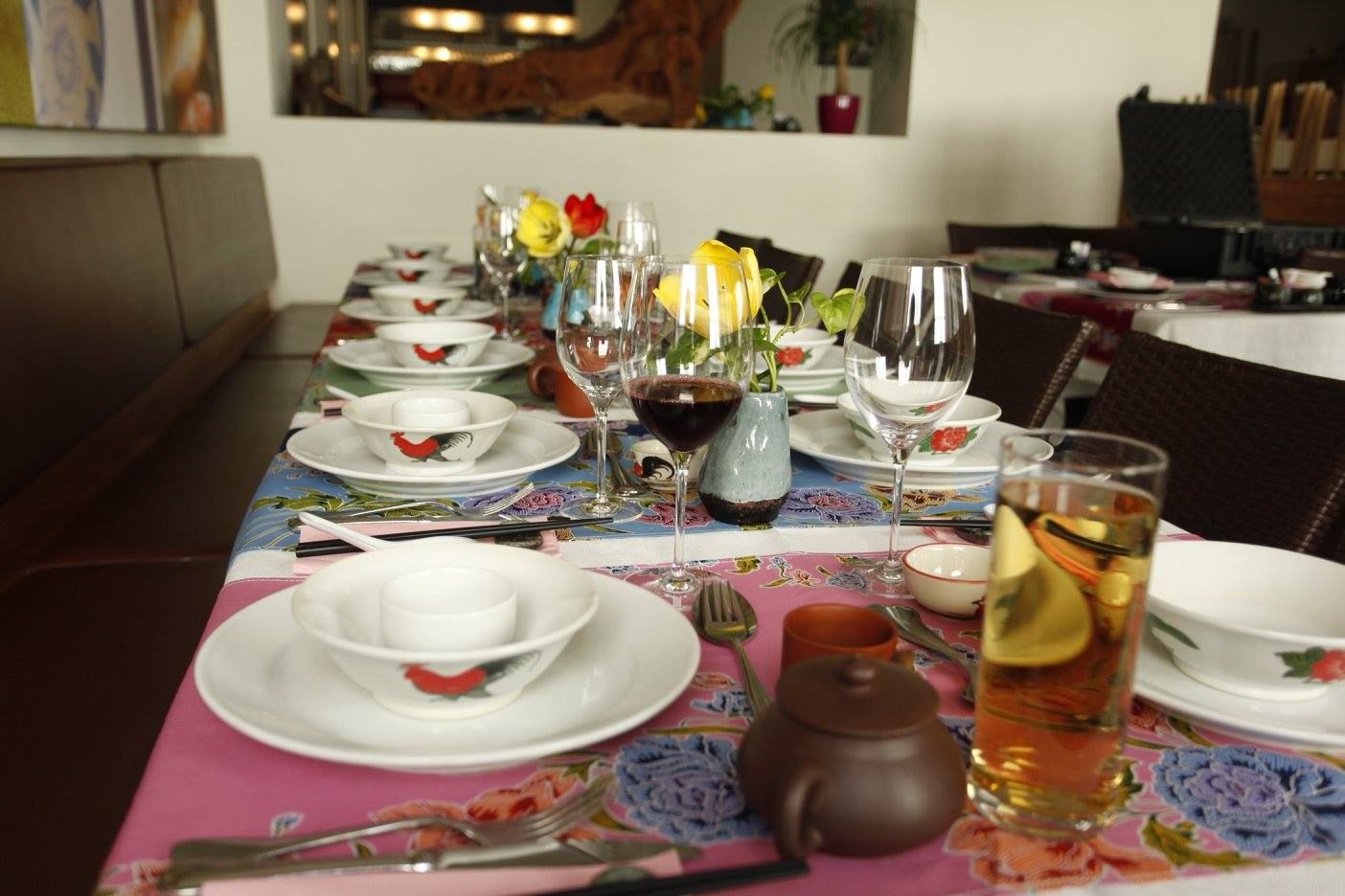 A set table in a restaurant with crockery, glasses and flowers.