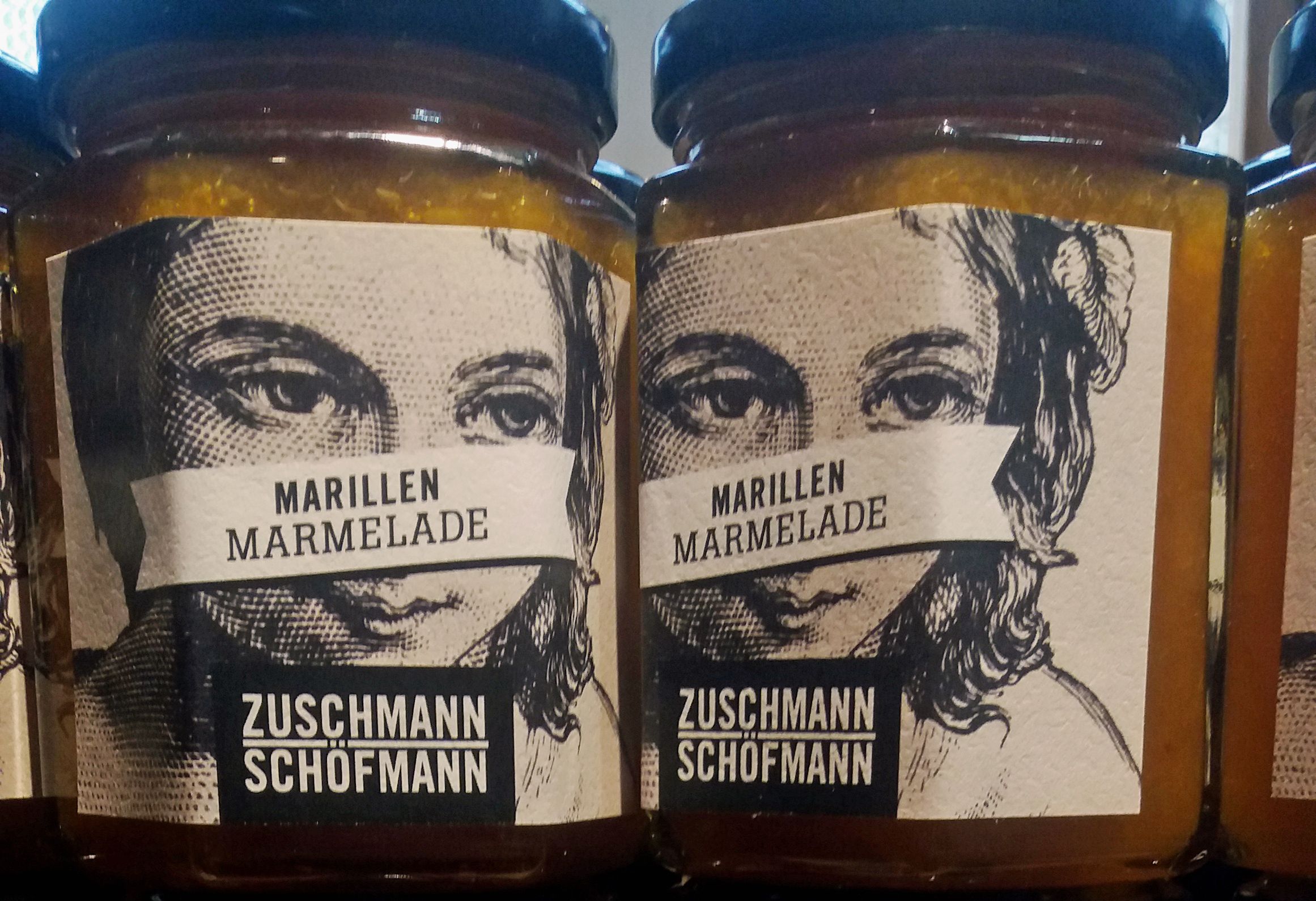 Two jars of apricot jam with labels showing a face.