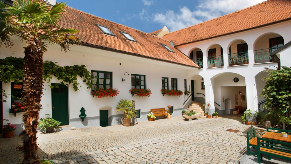 A traditional Austrian courtyard with white buildings, red tiled roofs and flowers.