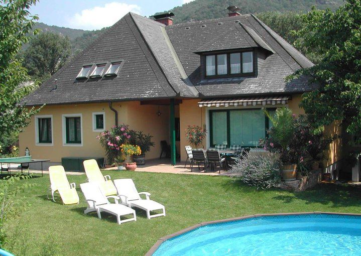 A house with a garden, pool and sun loungers.