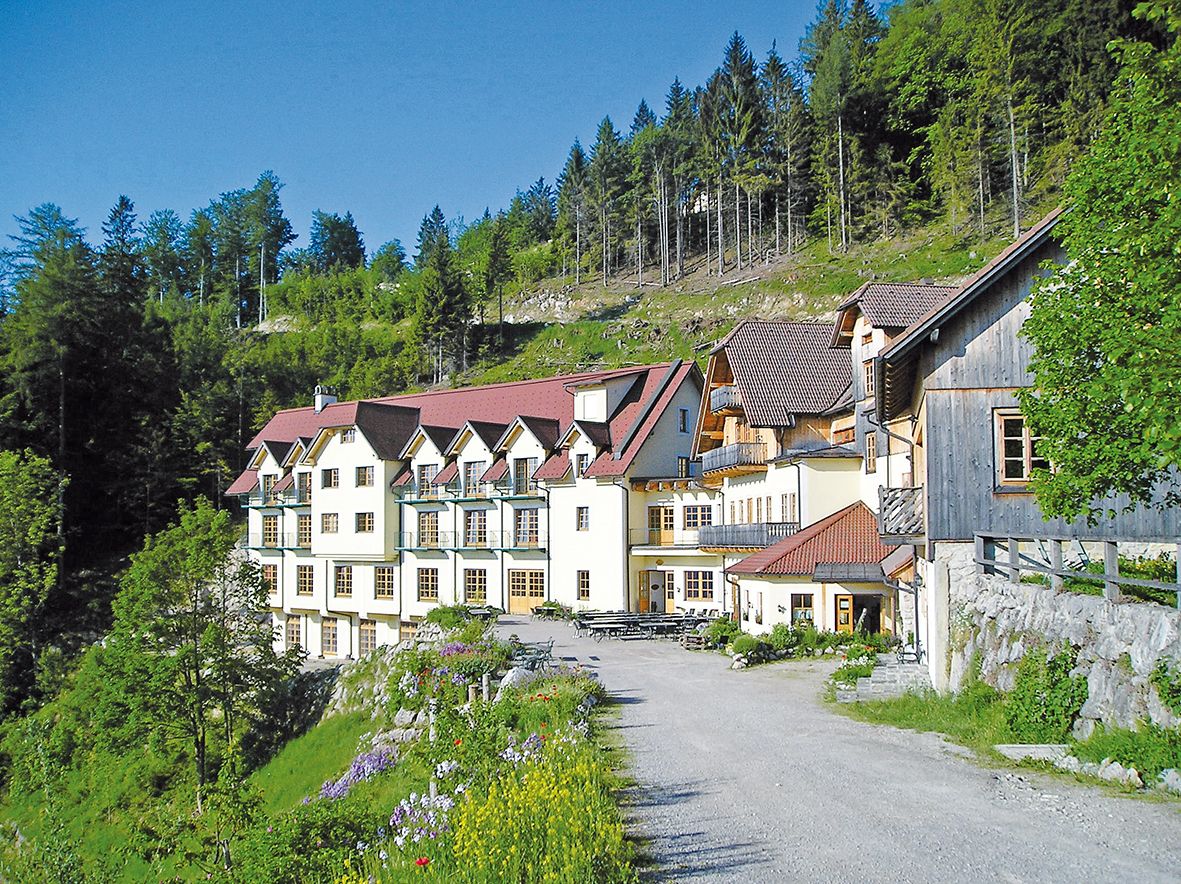 A large building with red roofs in a green, wooded setting.