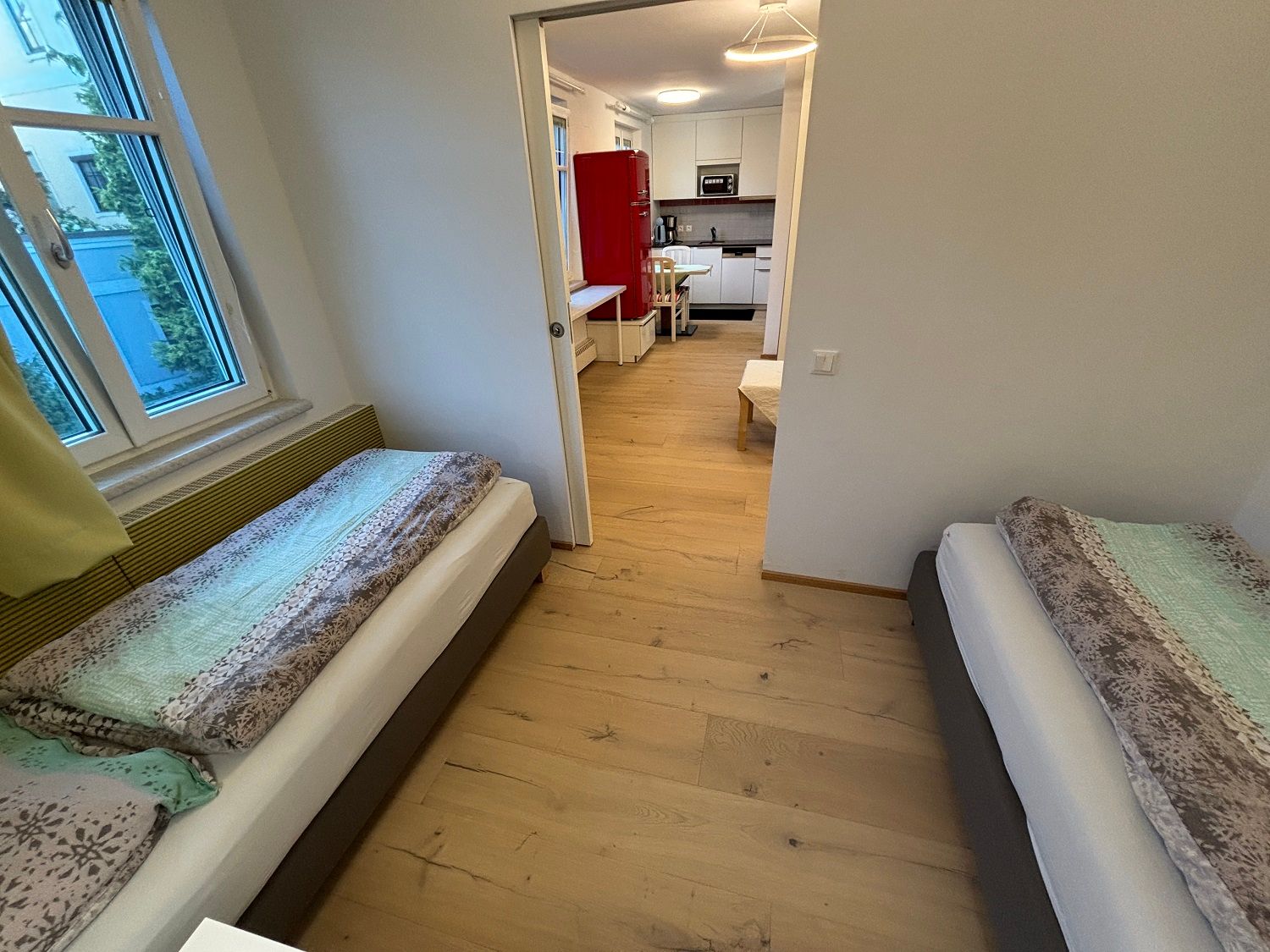Bedroom with two single beds and view into the kitchen.