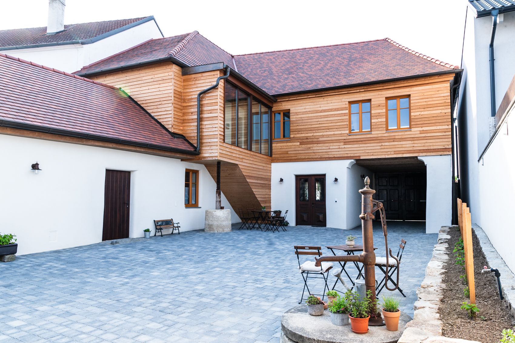 Inner courtyard of a guest house with wooden elements and paved floor.