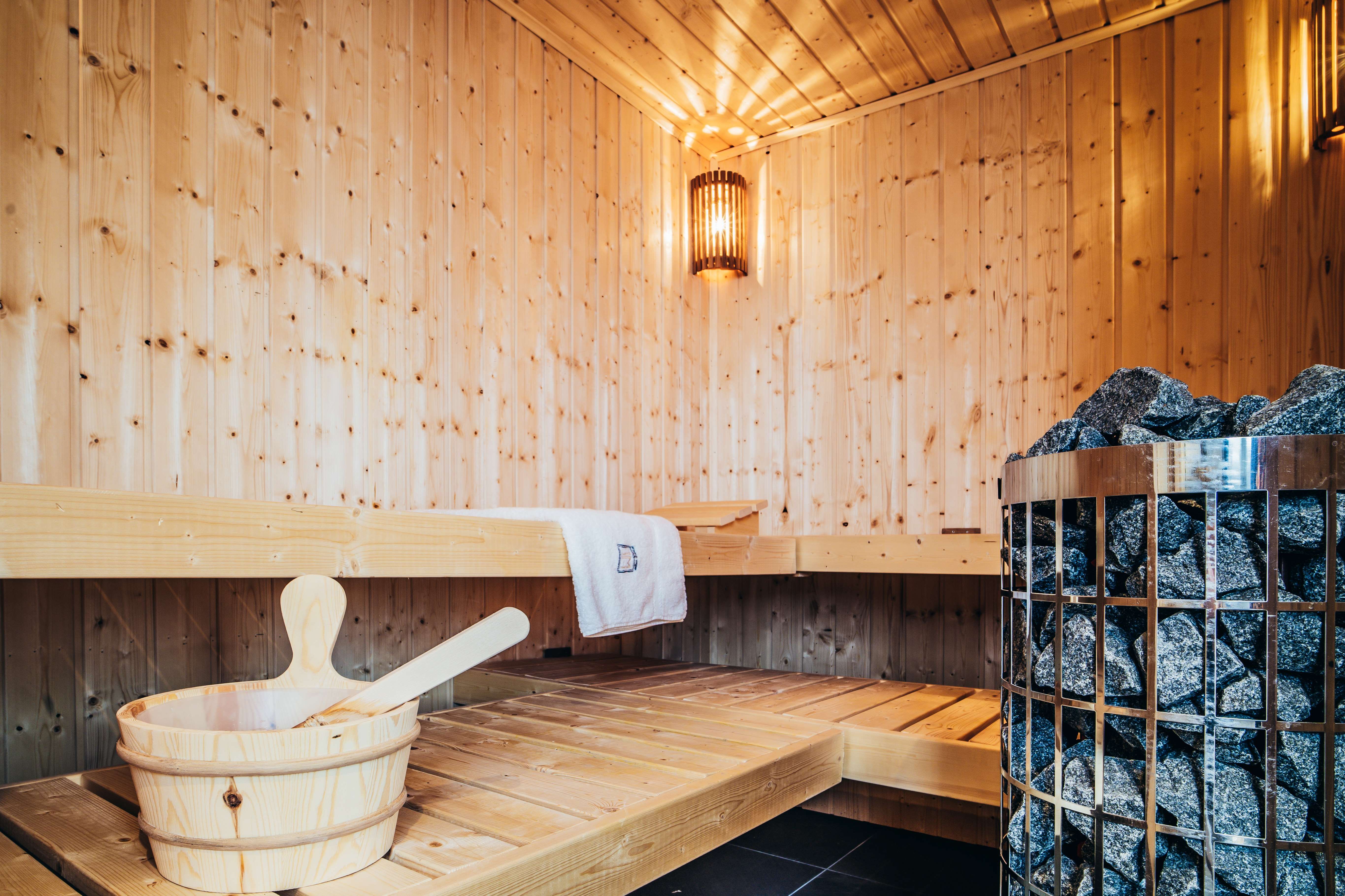 Interior view of a wooden sauna with sauna heater and wooden bucket.