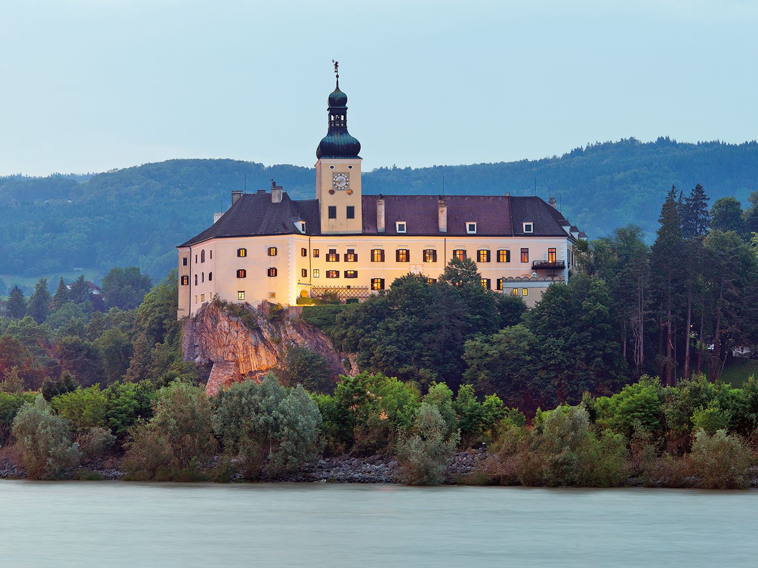 Persenbeug Castle on a hill with a river in the foreground.