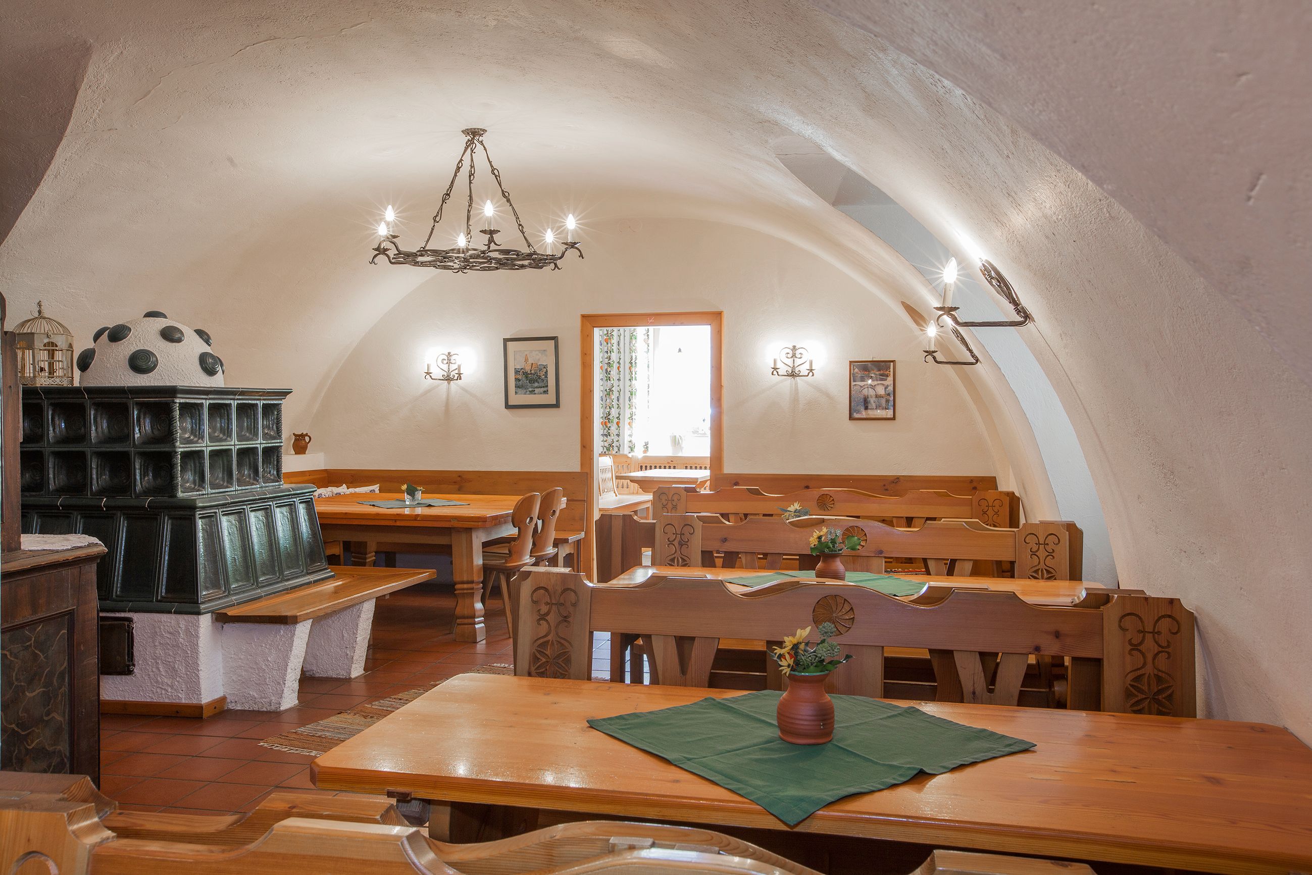 Interior view of a traditional wine tavern with wooden furniture and tiled stove.