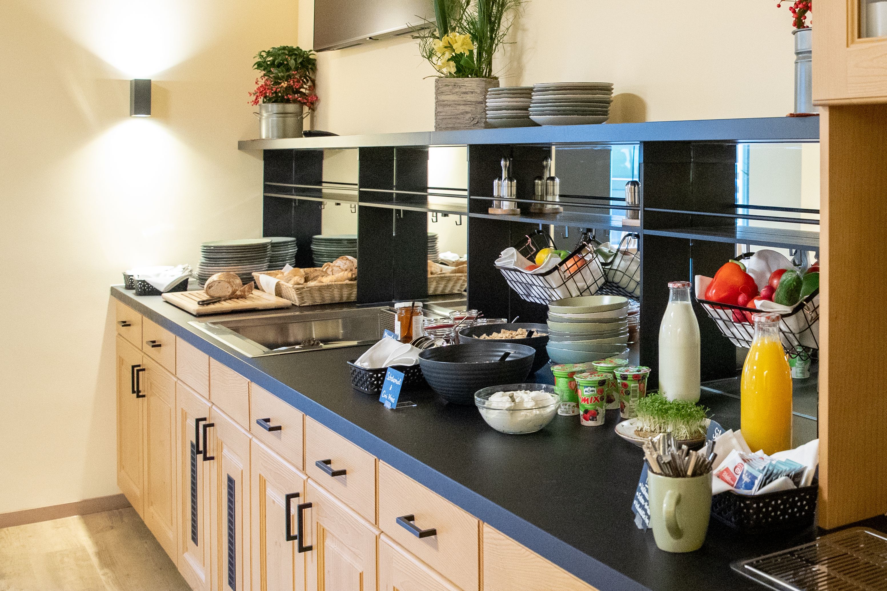 Breakfast buffet with bread, yogurt, juice and vegetables.