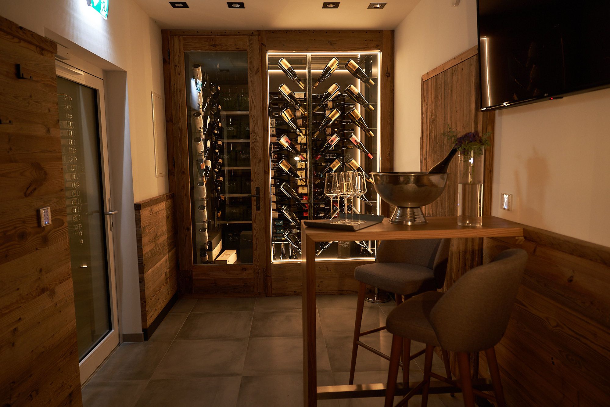 Wine cellar with bottle rack and bar table with glasses.