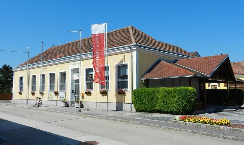 Municipal office in Rauchenwarth, yellow building with red roof and flowers.