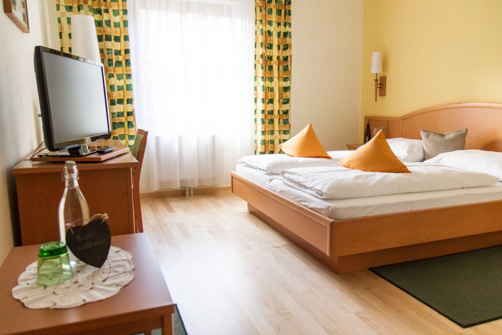 Comfortable hotel room with double bed, TV and curtains.