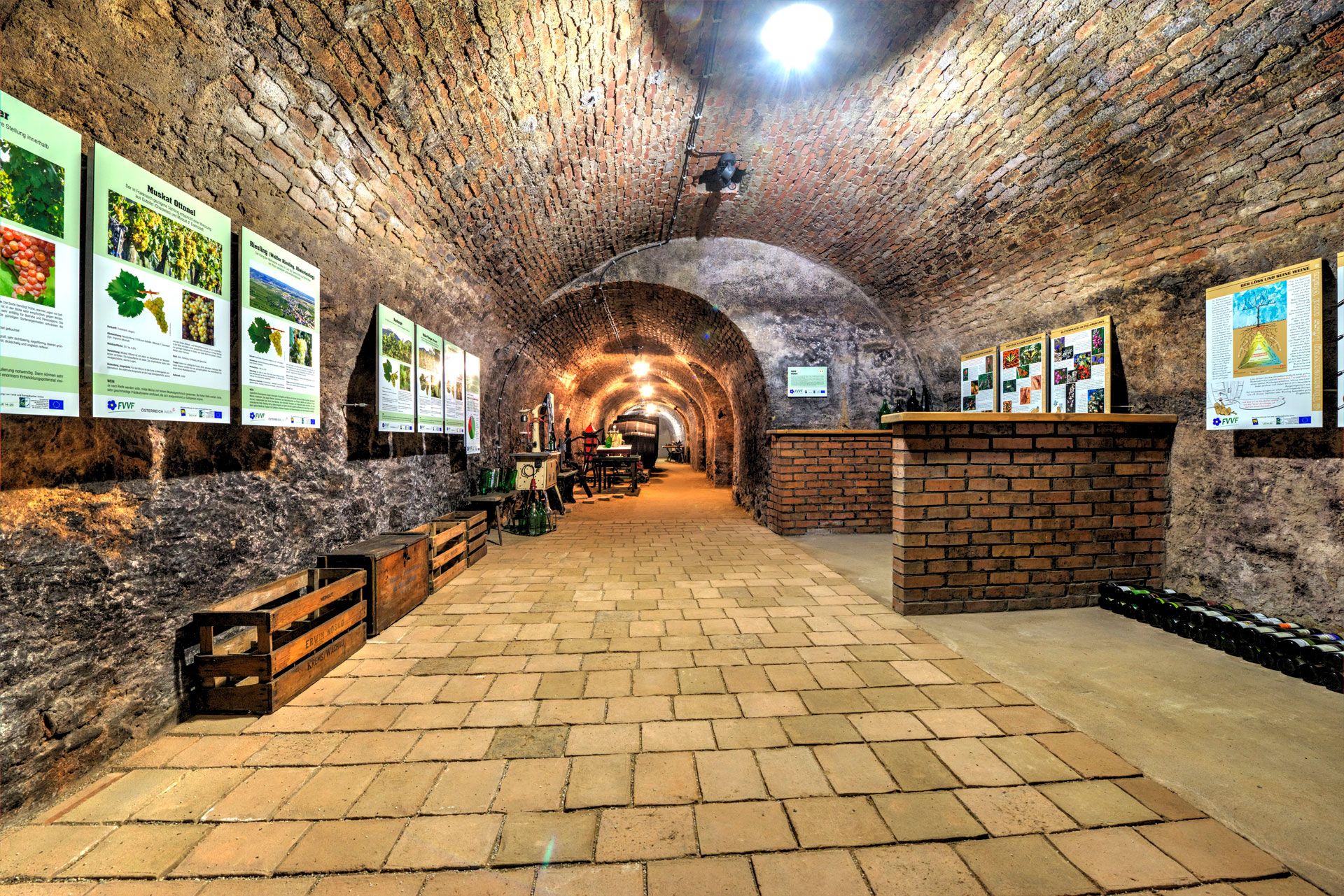A historic wine cellar with brick vaults and information posters on the walls.